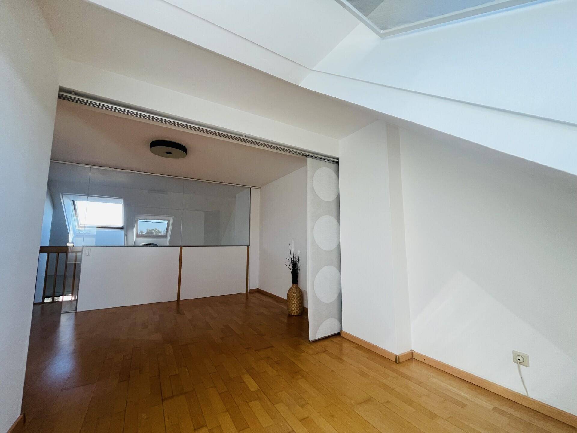 Heller Dachgeschossraum mit Glasabtrennung und Holzboden.