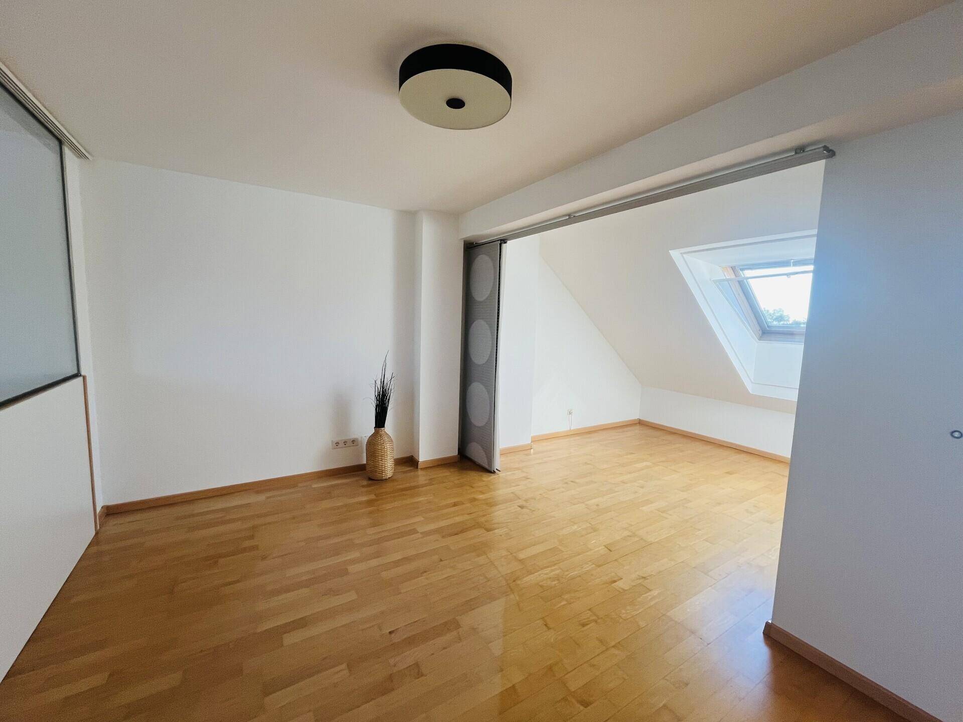 Heller Dachgeschossraum mit Holzboden und schrägen Wänden.