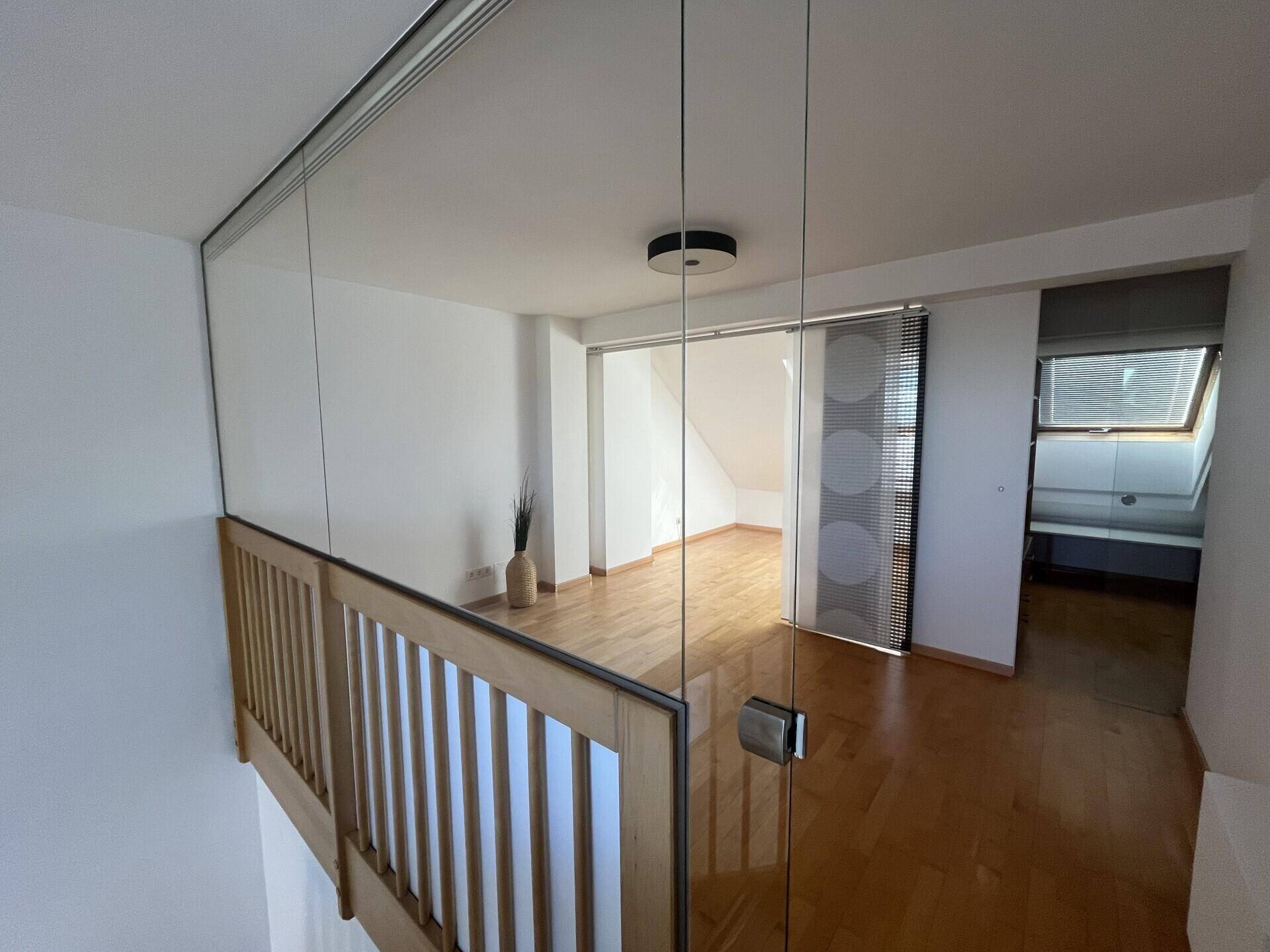 Offener Galeriebereich mit Glasgeländer und Blick auf die untere Etage.