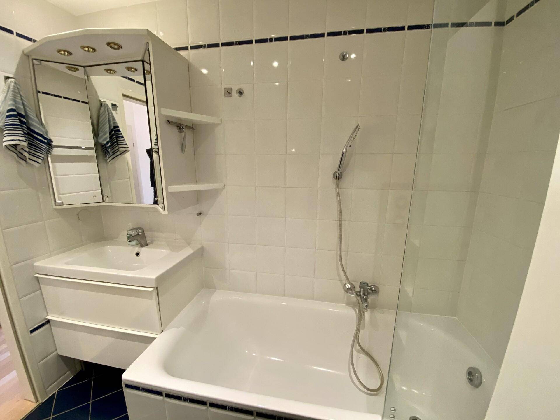 Badezimmer mit Badewanne, Waschbecken und Spiegelschrank.