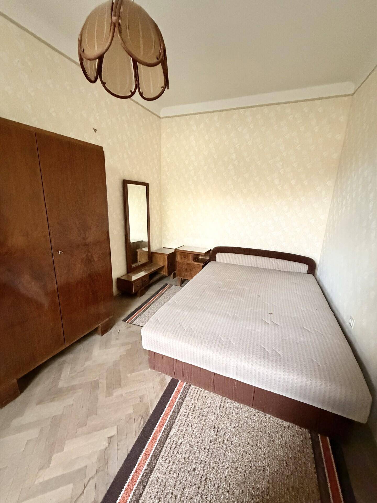 Schlafzimmer mit Doppelbett, großem Kleiderschrank und Spiegel in einem traditionellen Ambiente.