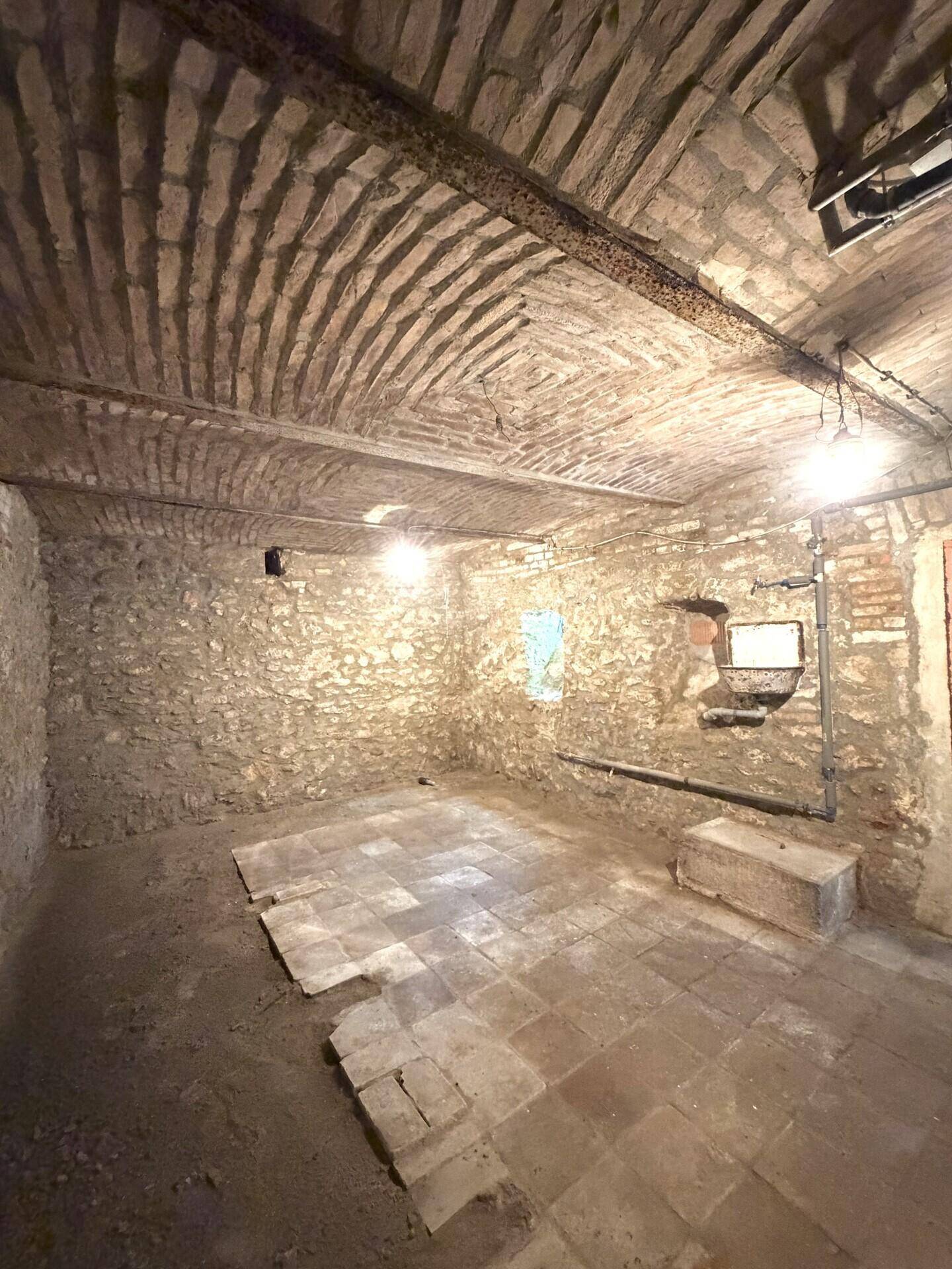 Historischer Keller mit robusten Steinmauern und einer beeindruckenden Ziegelgewölbedecke.