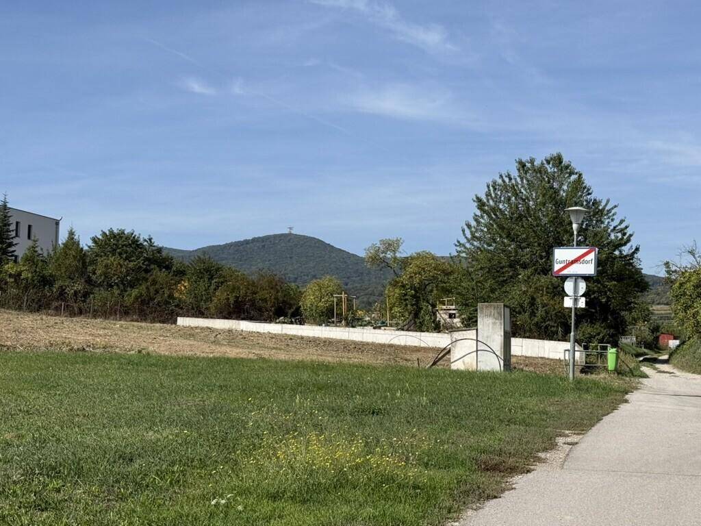 Weitläufiges Grundstück mit grüner Wiese und Blick auf bewaldete Hügel in der Ferne.