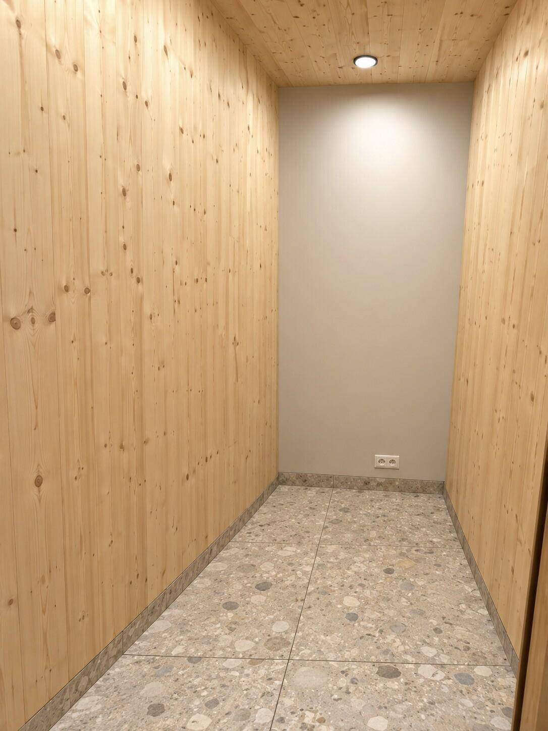 Praktischer Abstellraum mit Holzverkleidung an den Wänden und Fliesenboden.