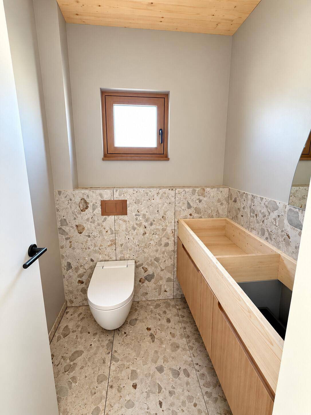 Gäste-WC mit modernen Terrazzo-Fliesen, Holzwaschtisch und Fenster.