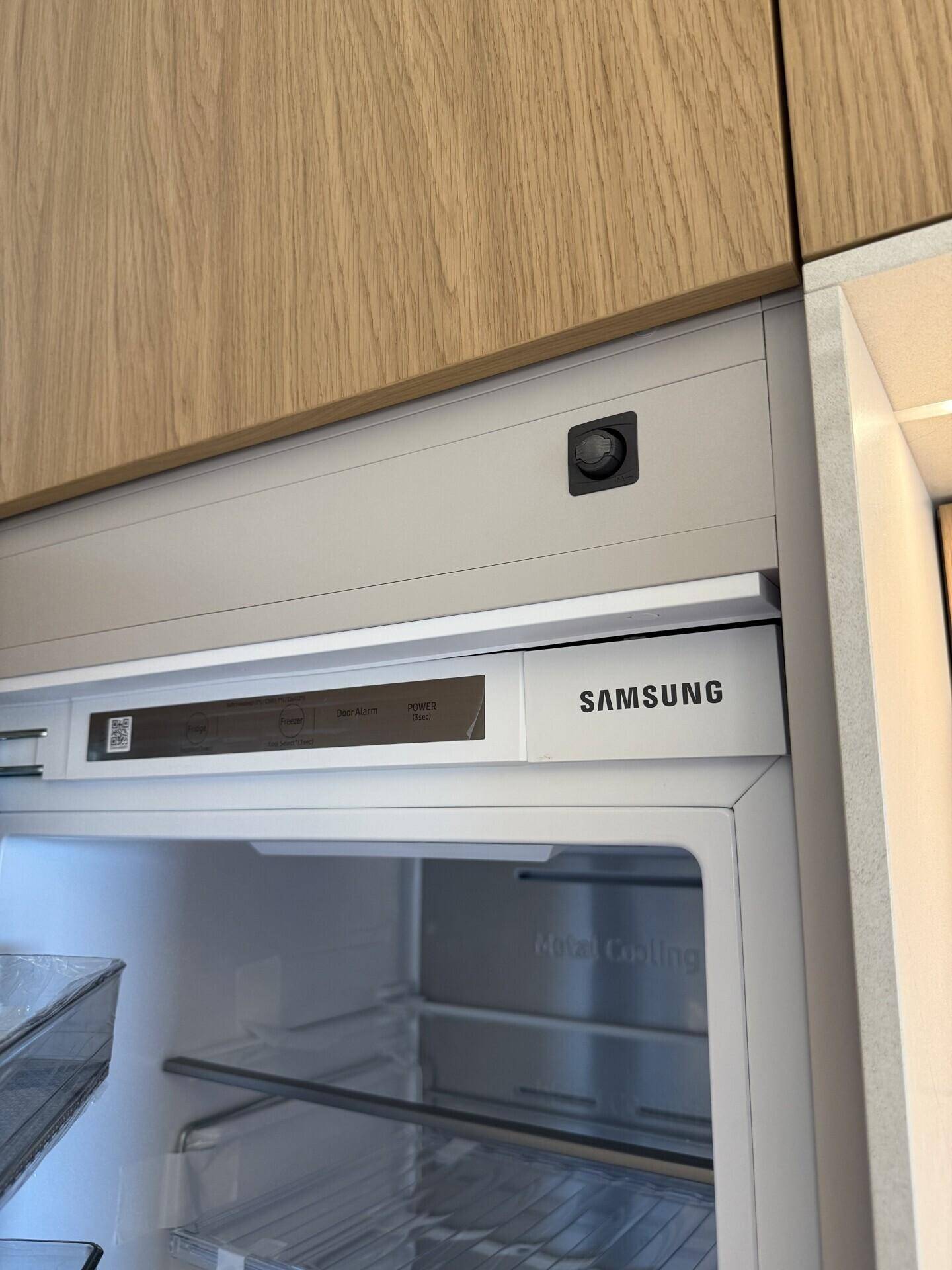 Eingebauter Kühlschrank der Marke Samsung in einer modernen Holzküche.