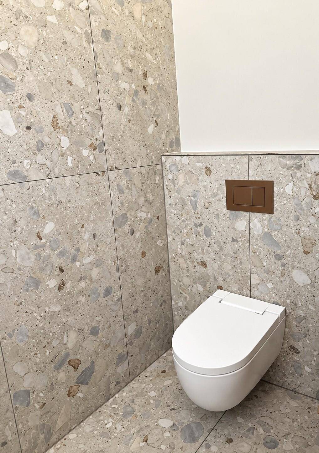 Wandhängendes WC mit modernen Terrazzo-Fliesen an Boden und Wänden.