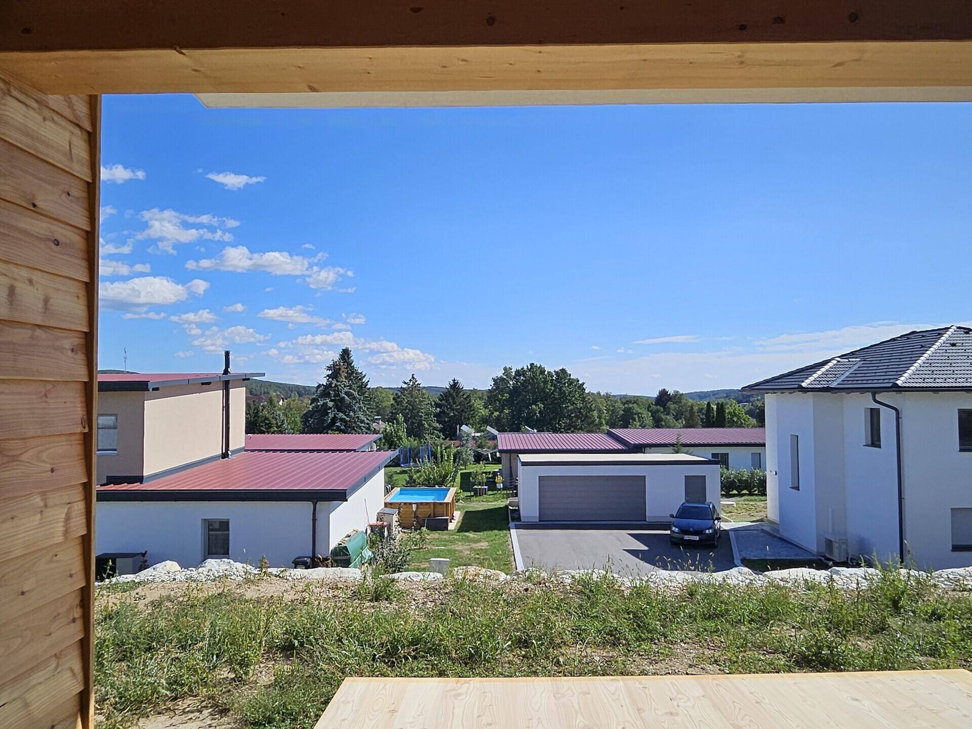 Weitläufiger Blick über die Nachbarschaft und grüne Landschaft von einer überdachten Terrasse.