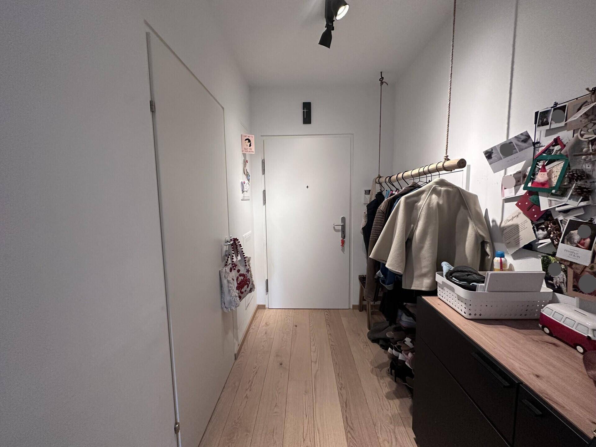 Heller Flur mit Holzfußboden, Garderobe und Kommode.