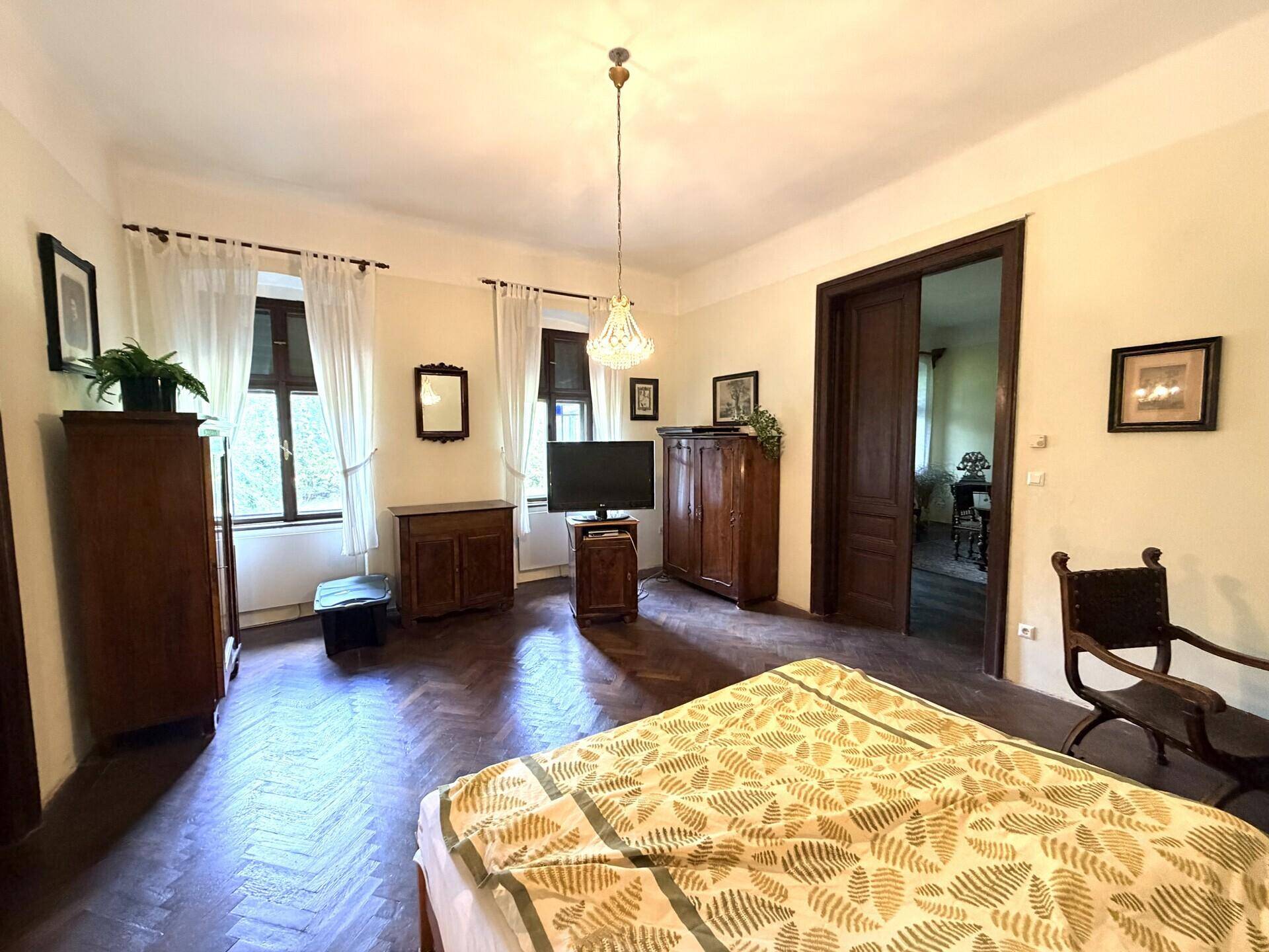 Helles Schlafzimmer mit Parkettboden, hohen Decken und traditionellen Holzmöbeln.