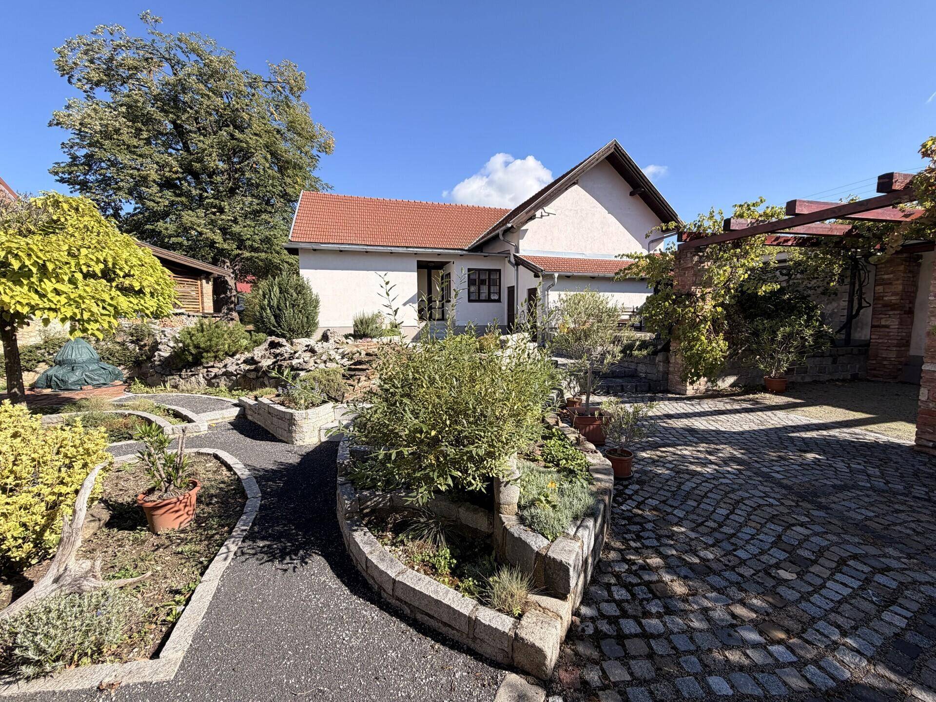 Gepflegter Gartenbereich mit Steinbeeten und Kopfsteinpflasterweg vor dem Haus.