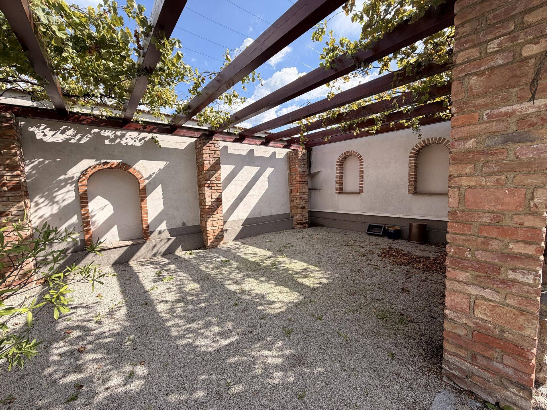 Überdachter Terrassenbereich mit Pergola und Ziegelwänden, ideal für entspannte Stunden.