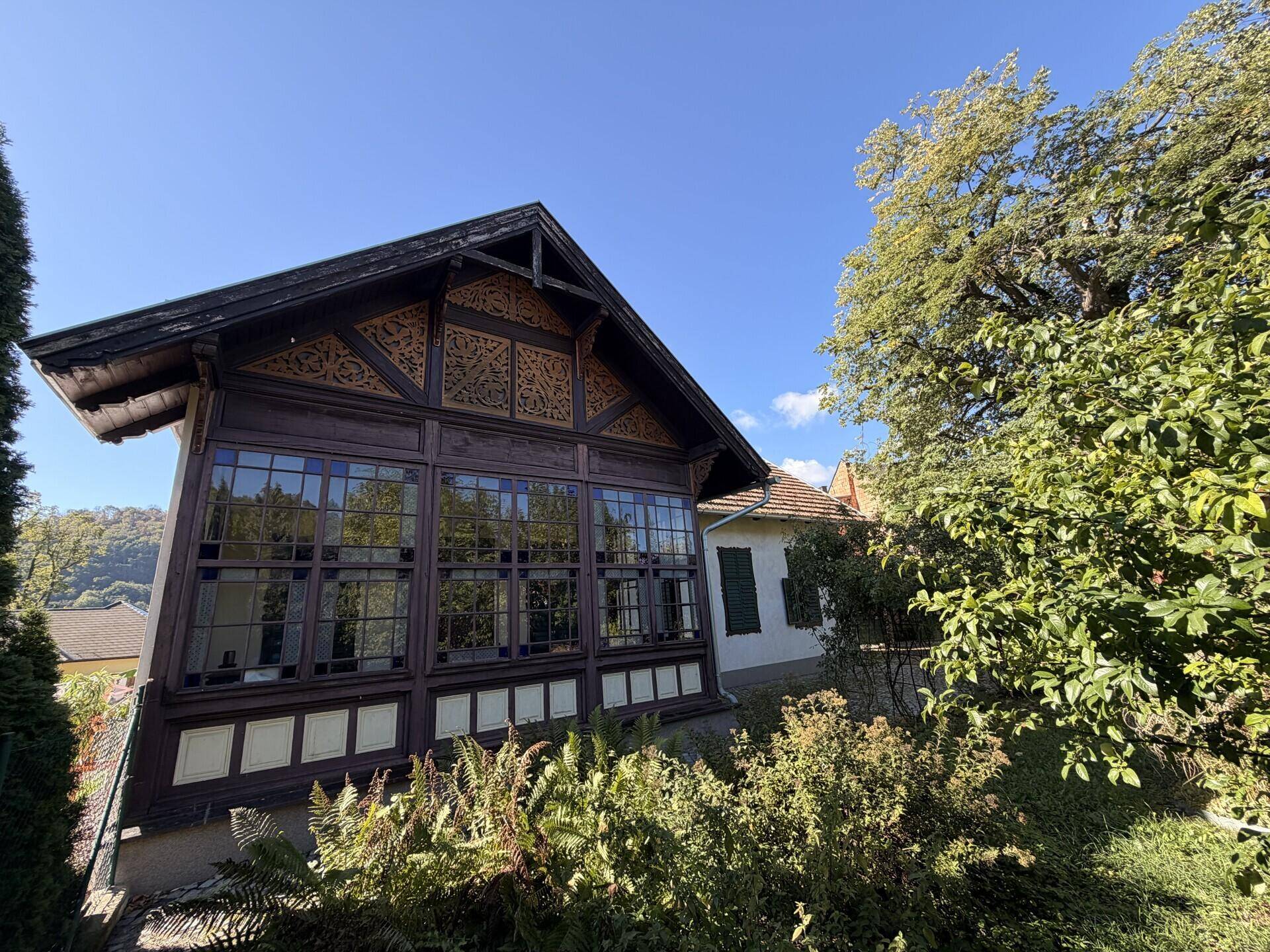 Historische Holzfassade des Hauses mit großen Fenstern und Blick auf die Umgebung.