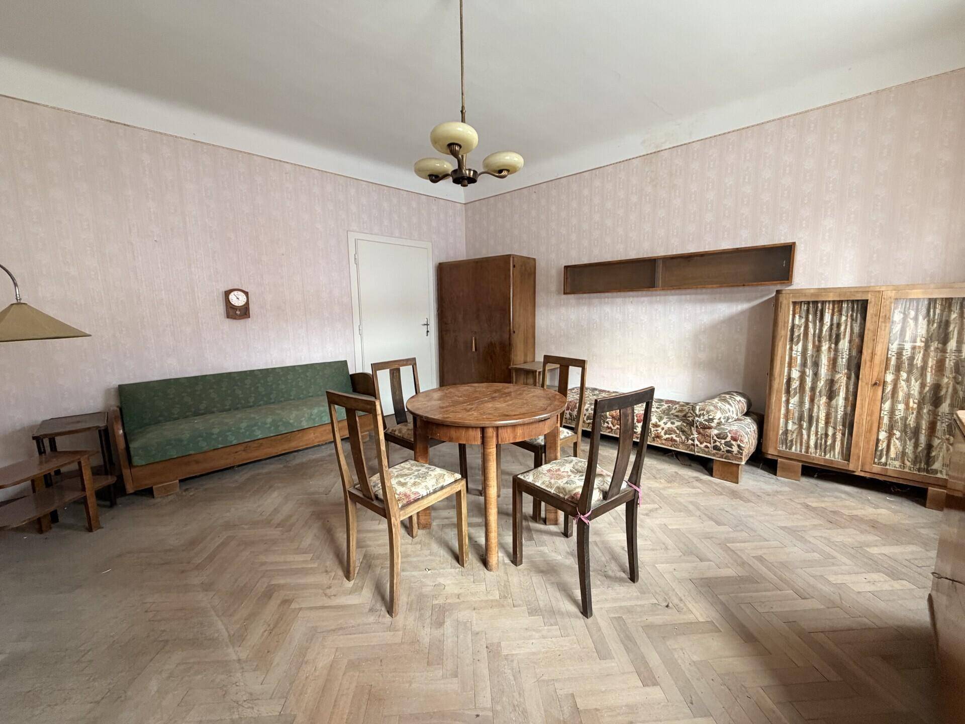 Geräumiger Wohn-Essbereich mit Fischgrätparkett, Vintage-Möbeln und heller Tapete.