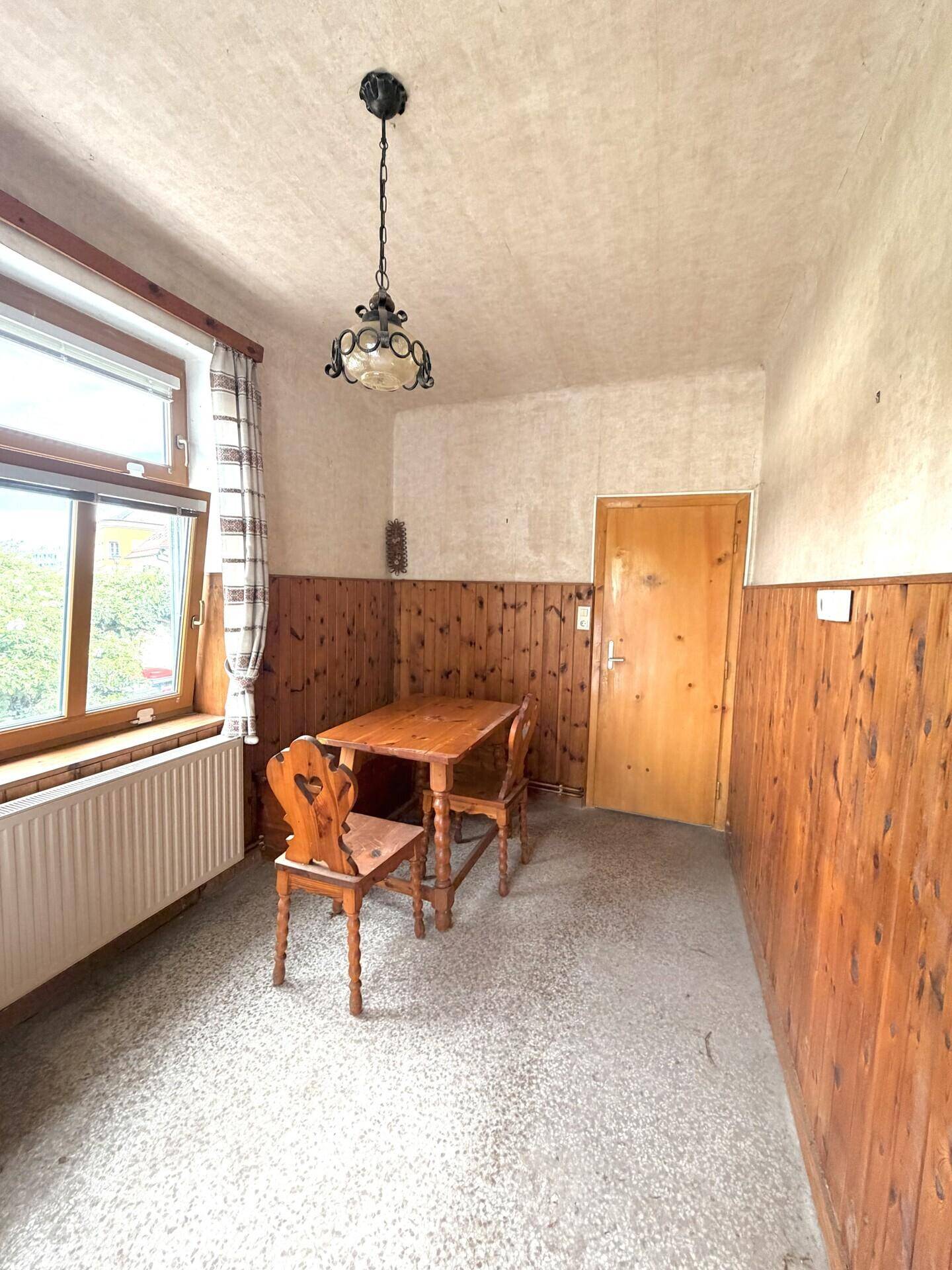 Kleiner Essbereich mit Holzvertäfelung, einem Fenster und einem einfachen Holztisch mit Stühlen.