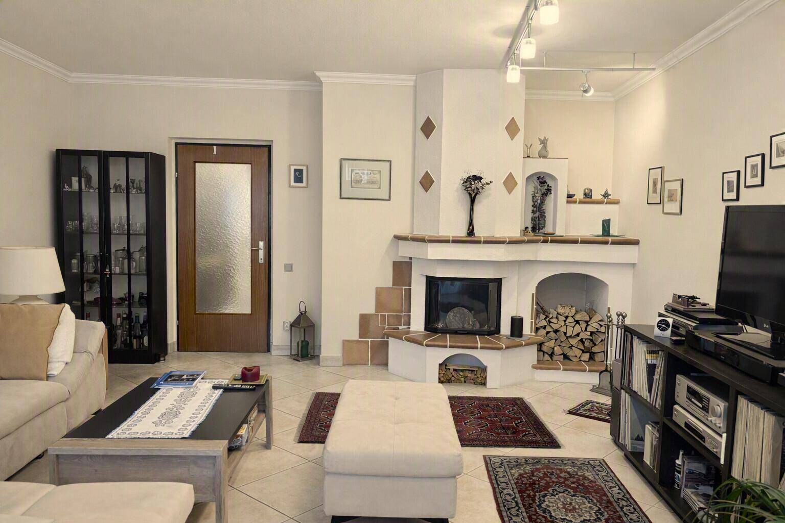 Gemütliches Wohnzimmer mit einem dekorativen Kamin, hellen Fliesen und bequemen Sofas.