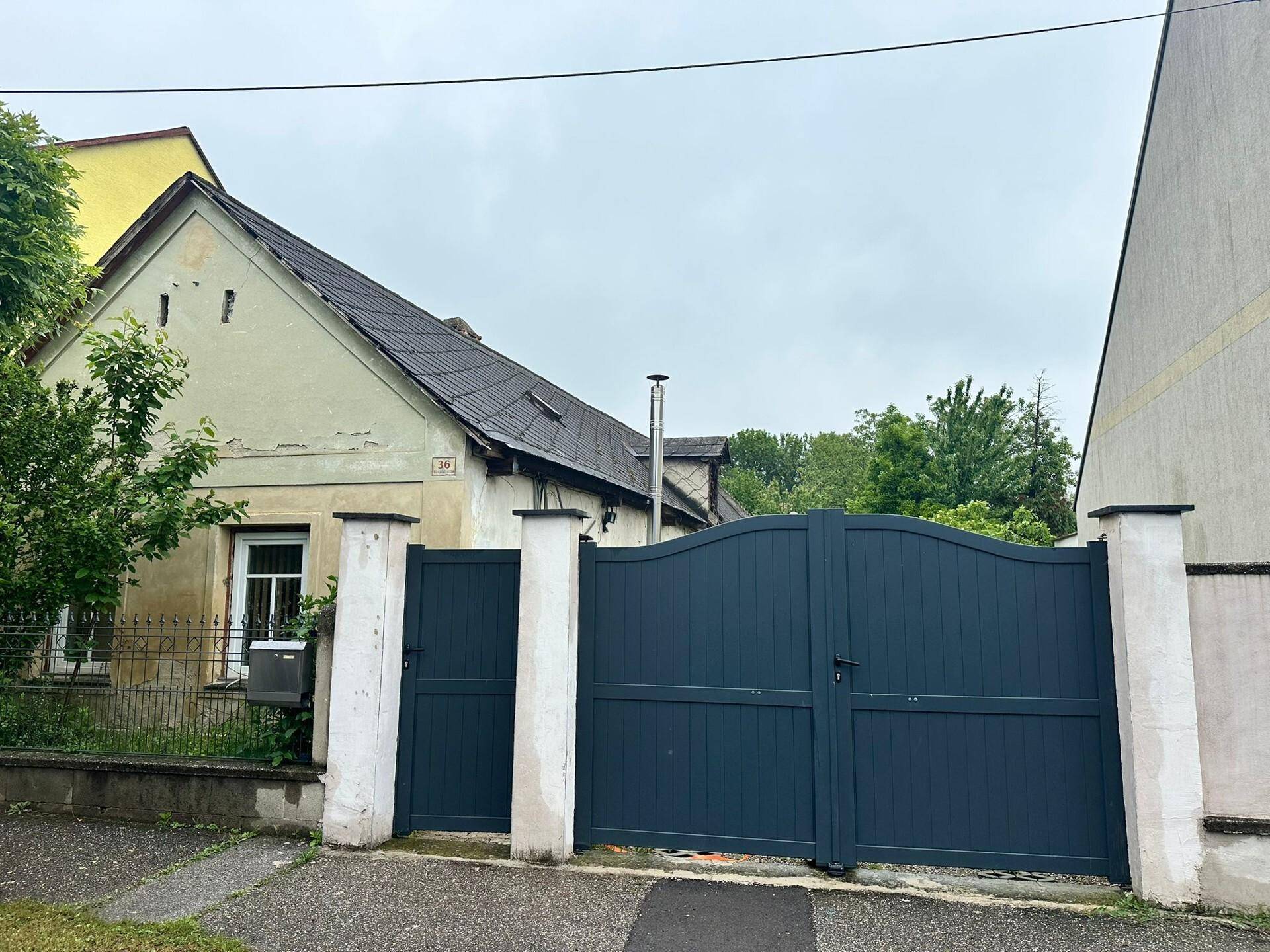 Älteres Wohnhaus mit dunklem Eingangstor und sichtbaren Gebrauchsspuren an der Fassade.