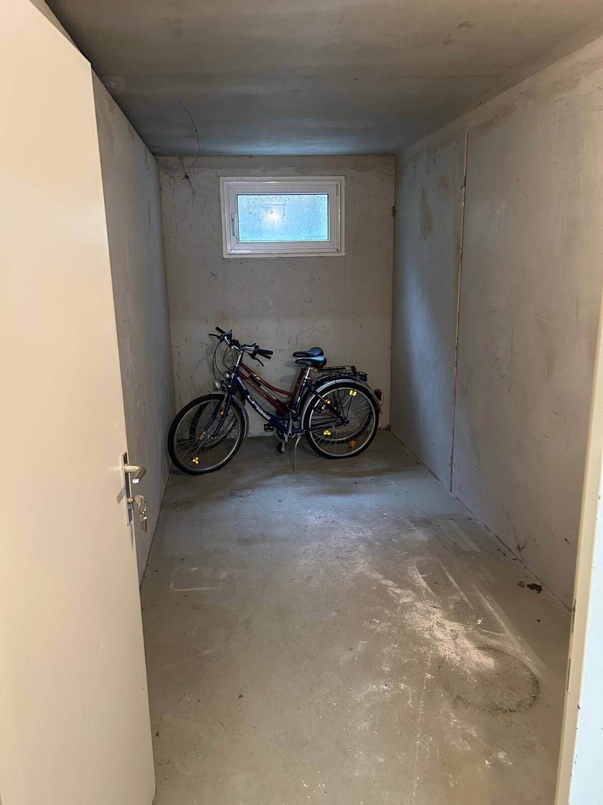 Leerer Abstellraum im Keller mit einem kleinen Fenster und Betonboden.