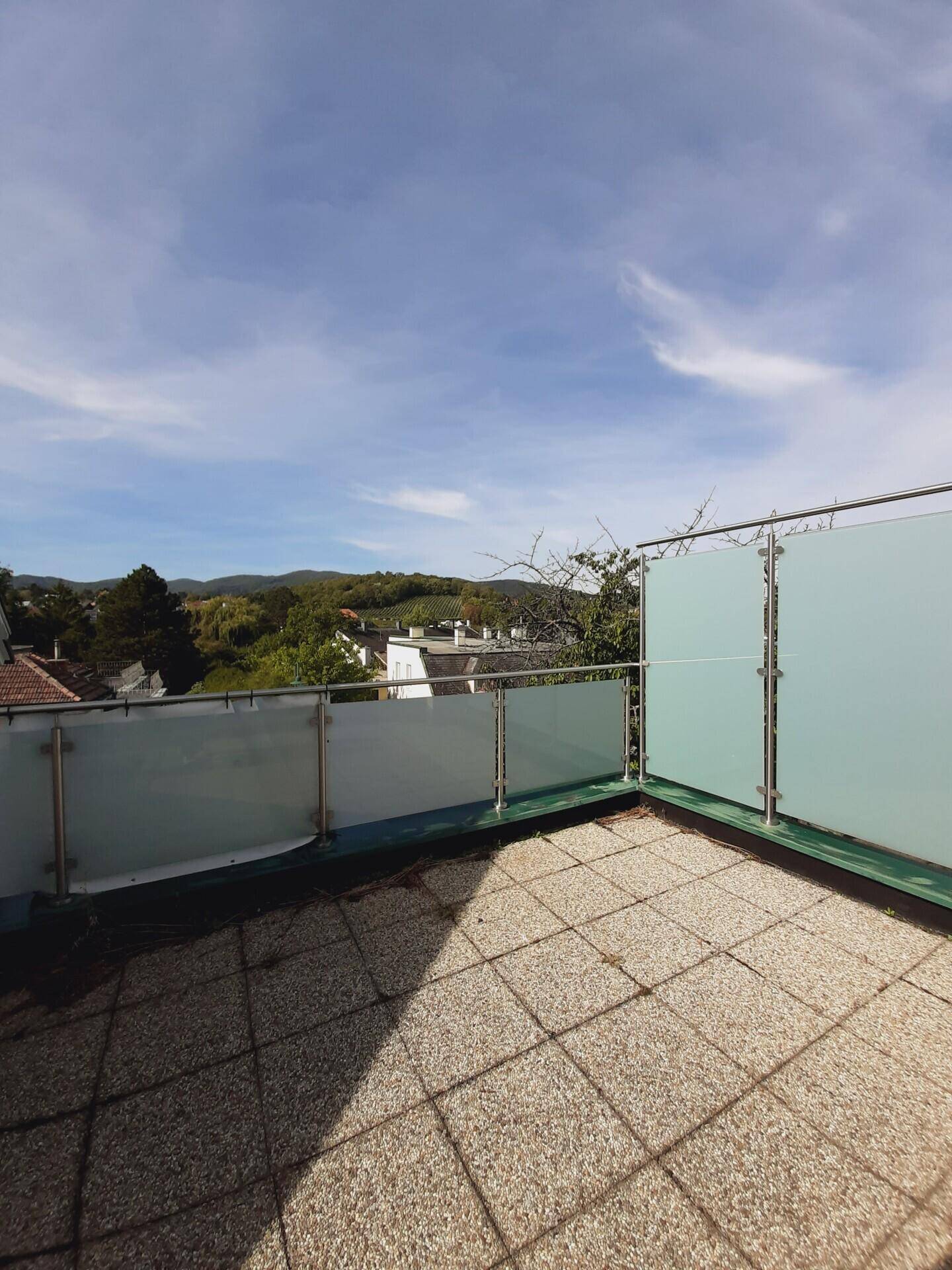 Geräumige Dachterrasse mit Fliesenboden und weitem Blick über die grüne Umgebung.