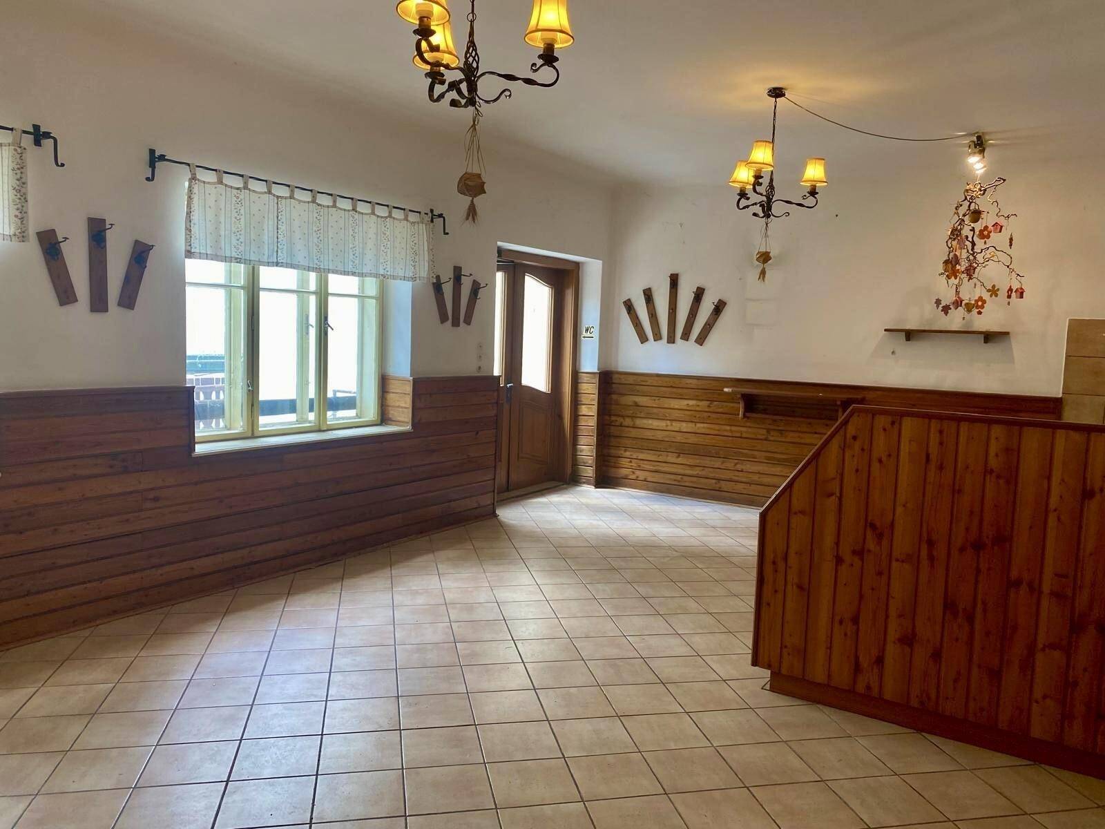 Geräumiger Raum mit Holzvertäfelung, Fliesenboden und traditionellen Deckenleuchten.