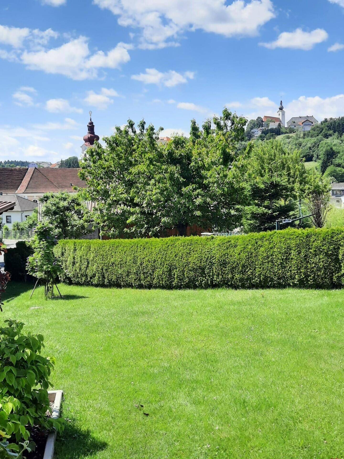 Weitläufiger Rasengarten mit Gartenhaus und Panoramablick auf die malerische Umgebung.