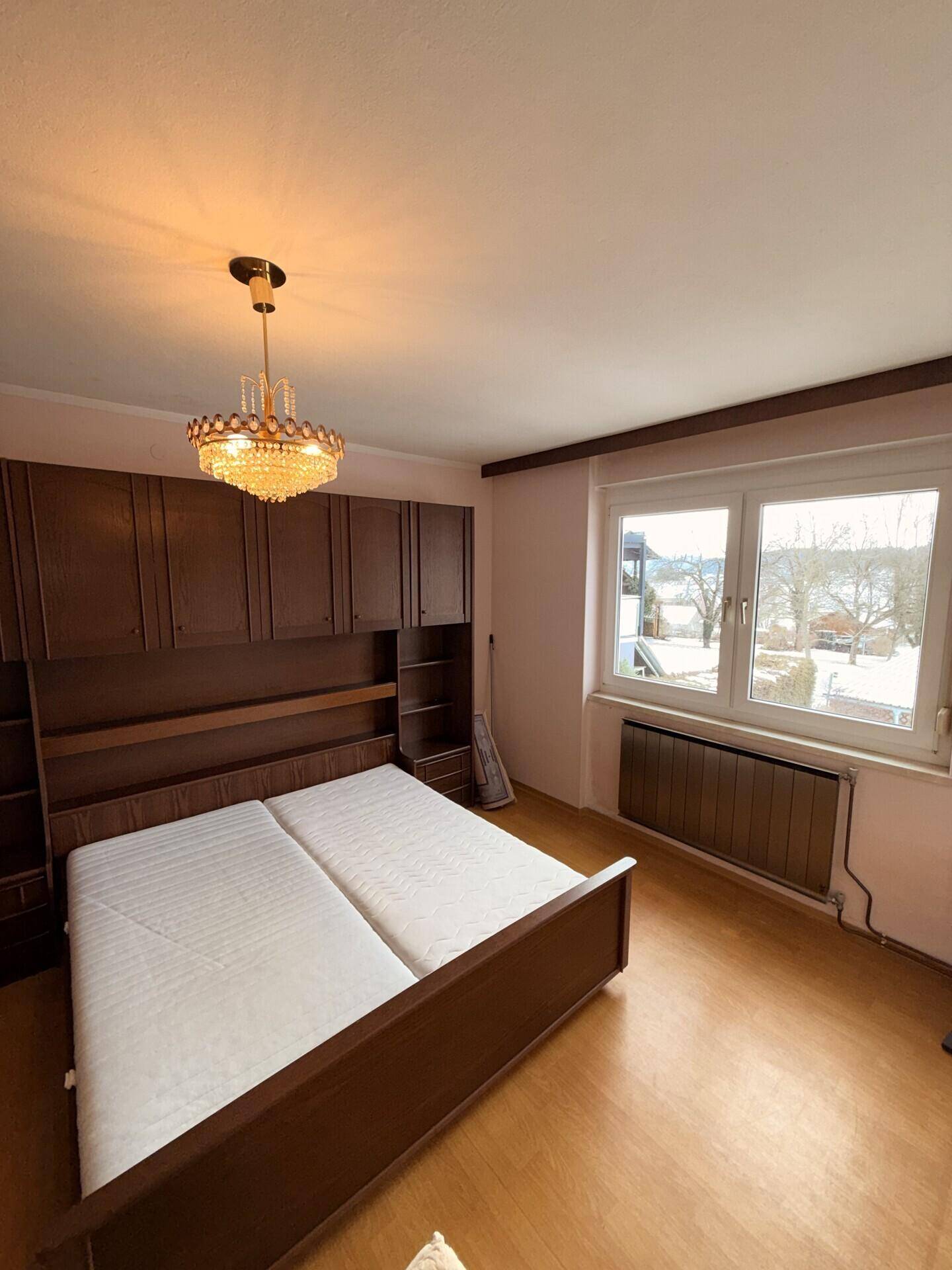 Schlafzimmer mit Einbauschränken, Doppelbett und Fenster, bietet natürlichen Lichteinfall.