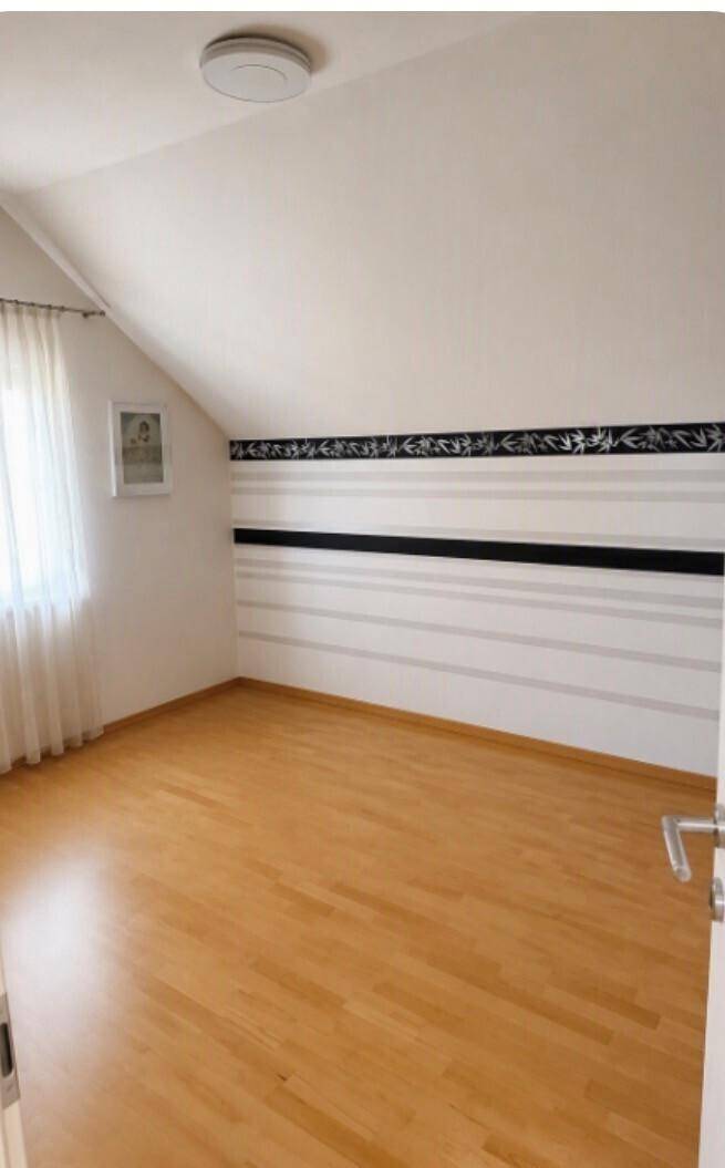 Helles Schlafzimmer mit Dachschrägen und Laminatboden, bereit zur individuellen Gestaltung.