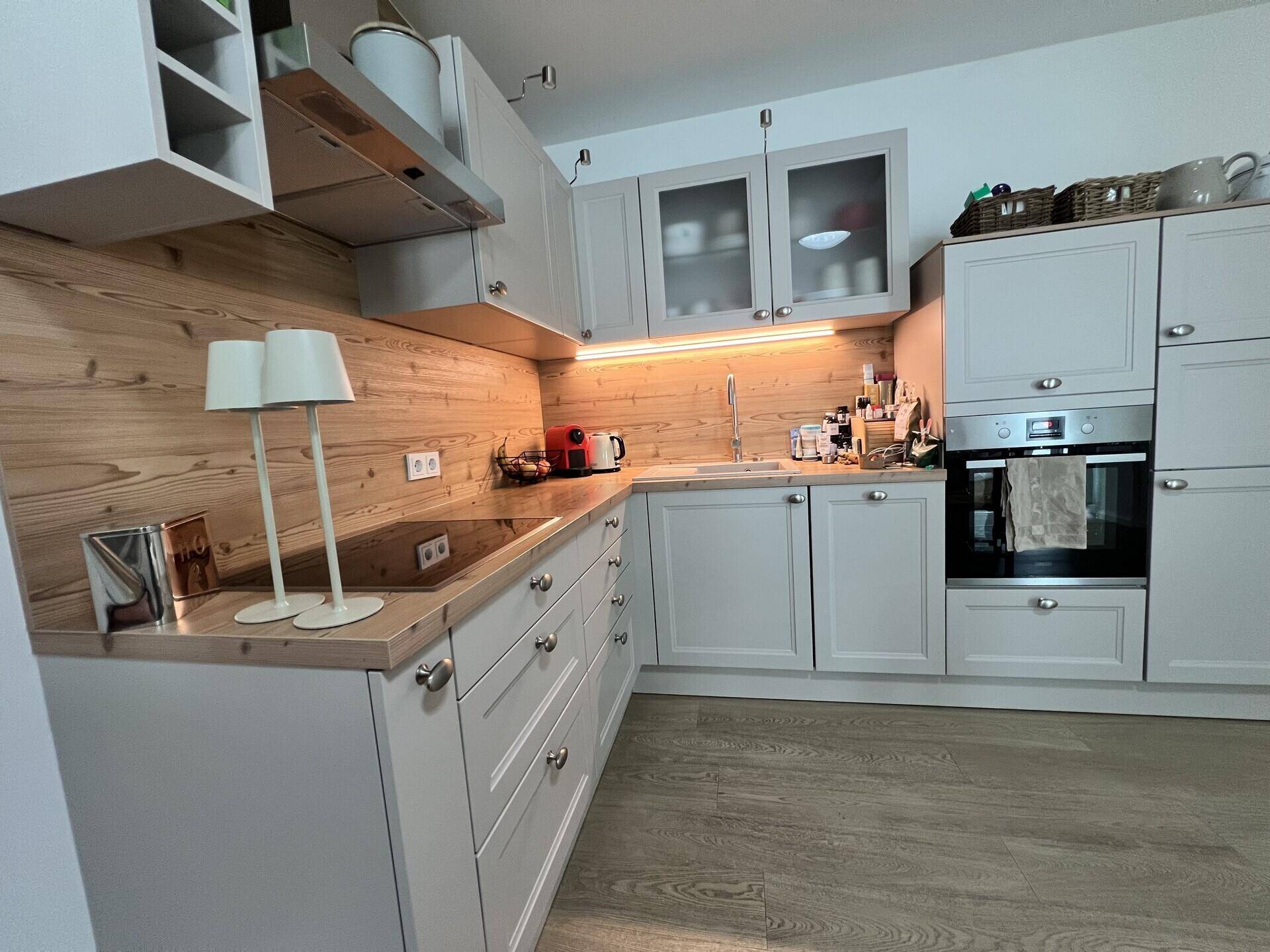 Gut ausgestattete Küche mit hellen Fronten, Holzdetails und modernen Kochfeldern.