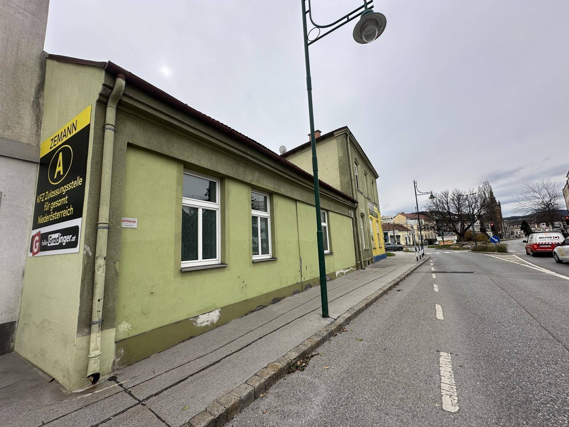 Seitenansicht des Gebäudes mit grüner Fassade und Fenstern entlang der Straße.