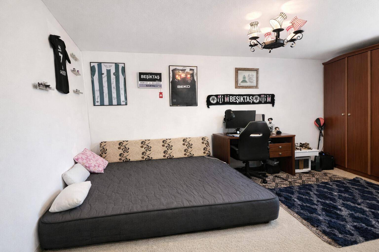 Jugendzimmer mit Schlafsofa, Schreibtisch und persönlichen Dekorationen an den Wänden.