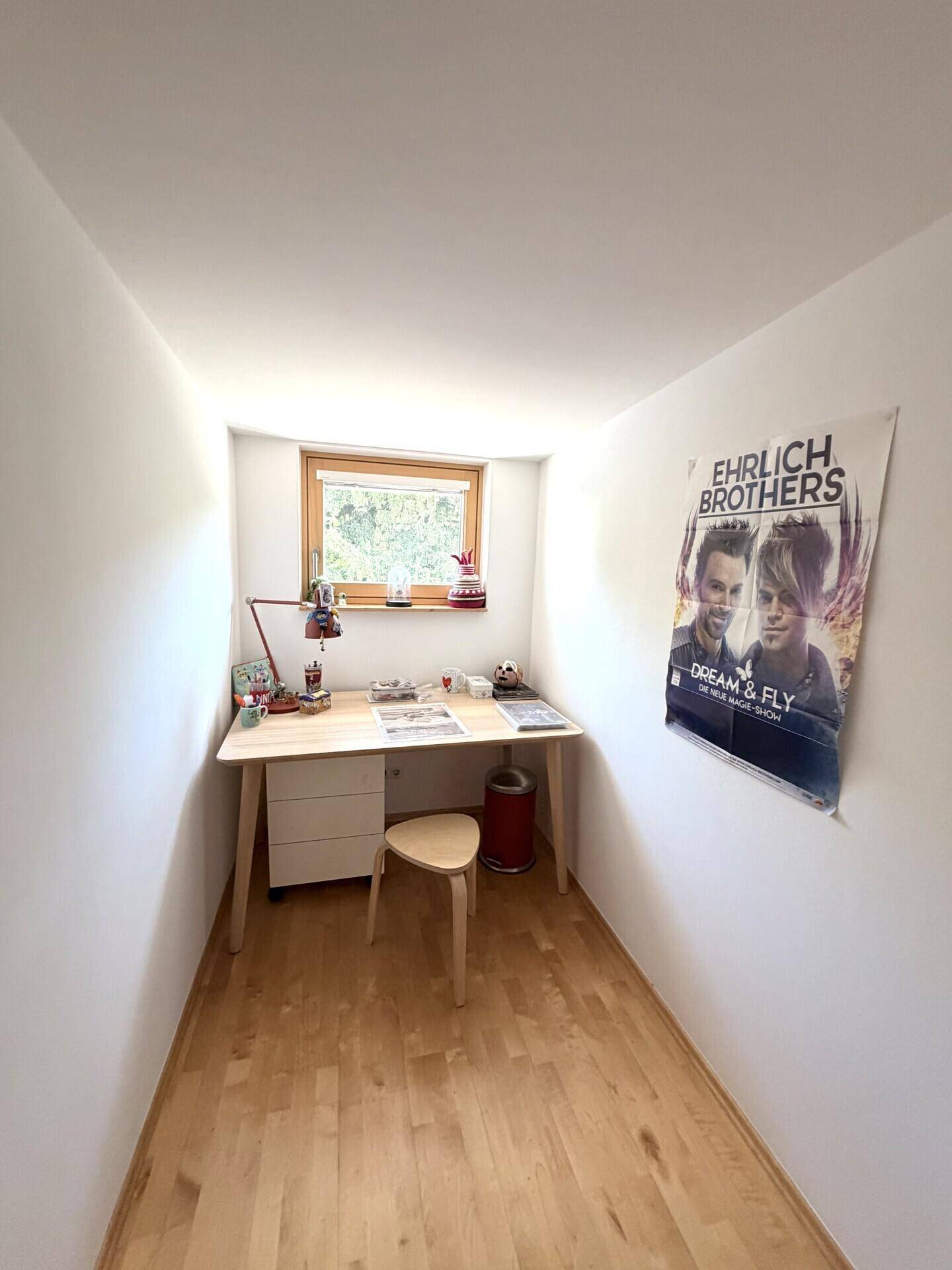 Kleines Arbeitszimmer mit Schreibtisch, Holzboden und Fenster, ideal für konzentriertes Arbeiten.
