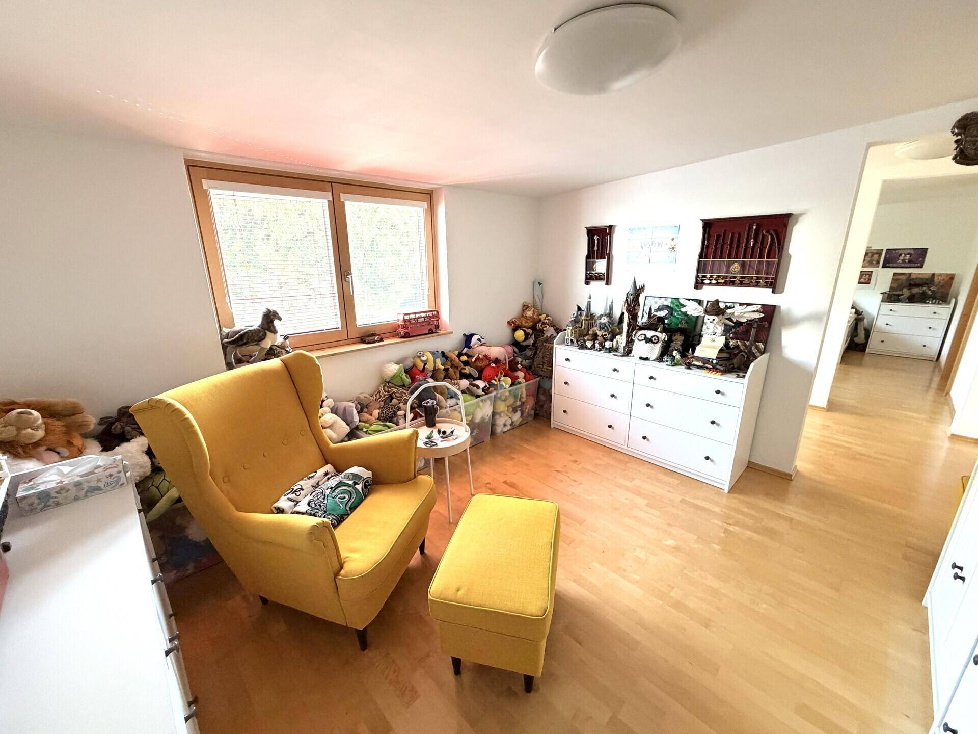 Gemütlicher Raum mit gelbem Sessel, Holzboden und Fenster, ideal zum Entspannen.
