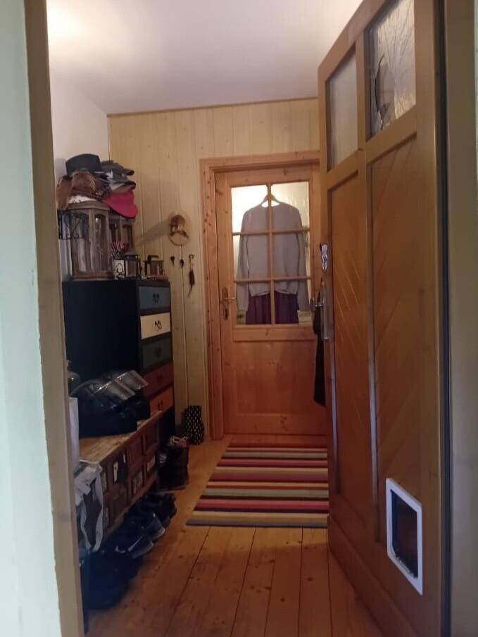 Eingangsbereich mit Holzvertäfelung, Holzboden und Stauraum für Schuhe und Kleidung.