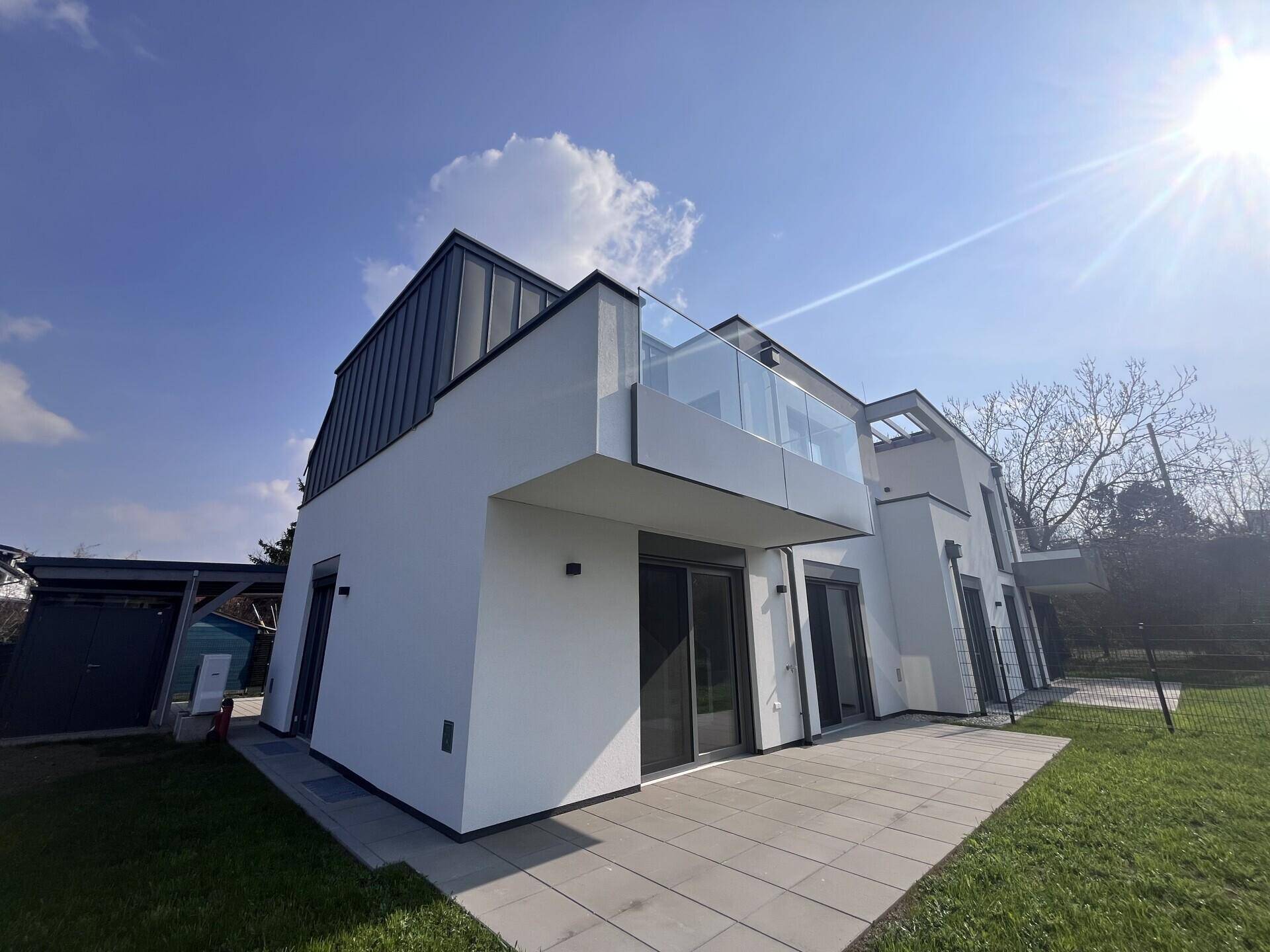 Rückseite der modernen Doppelhaushälfte mit sonniger Terrasse, Balkon und weitläufigem Garten.