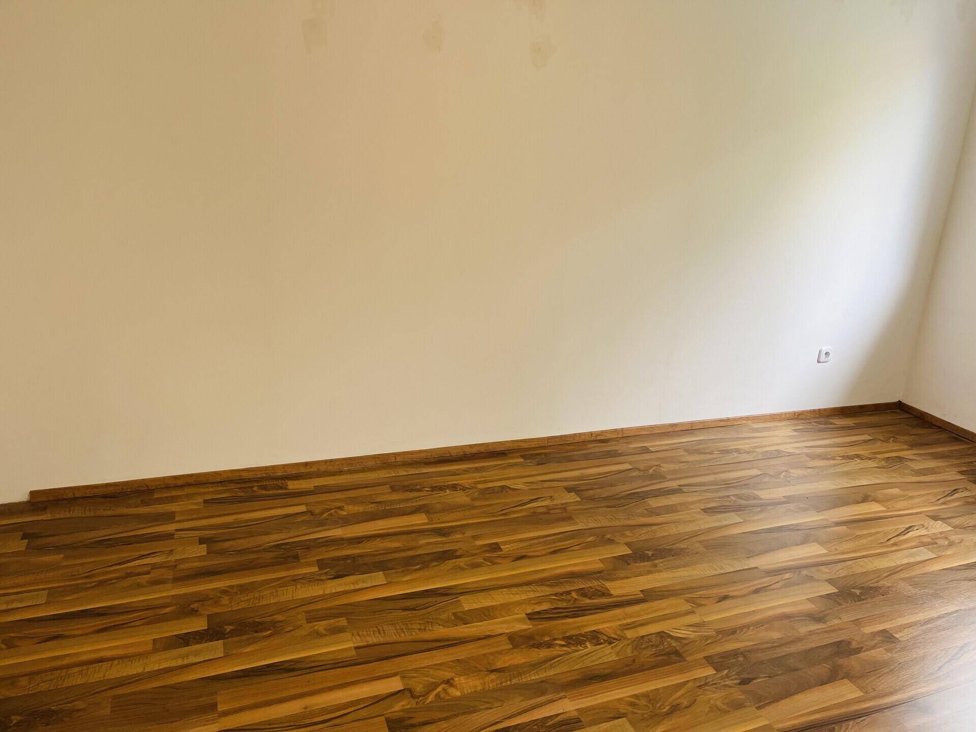 Schlafzimmer mit Laminatboden und neutralen Wänden, bereit zur individuellen Gestaltung.