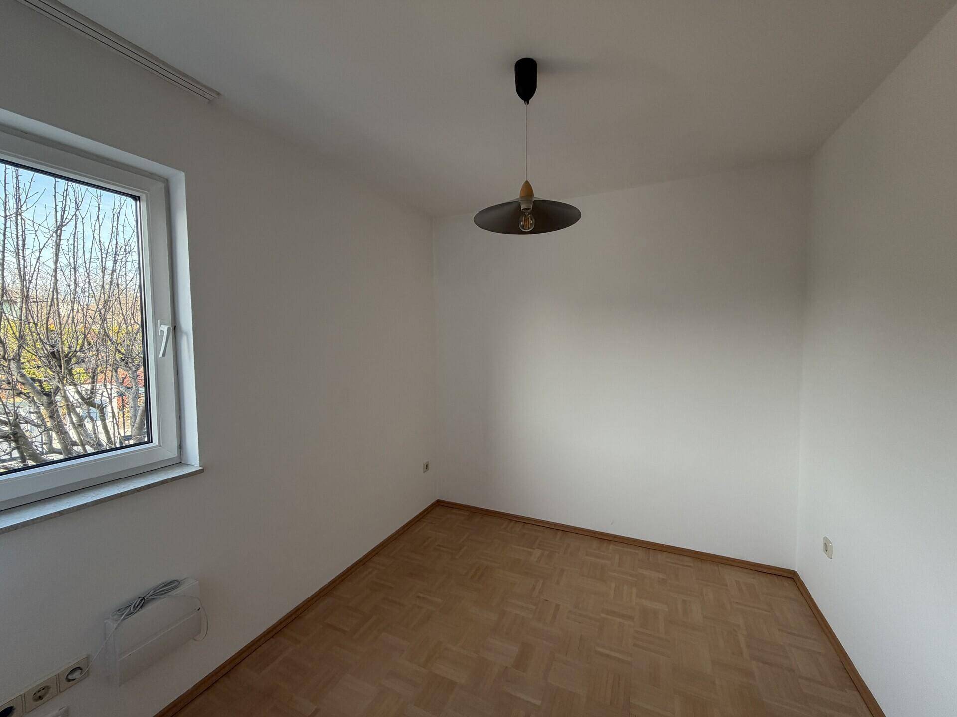 Heller Raum mit Parkettboden und Fenster, geeignet als Schlaf- oder Gästezimmer.
