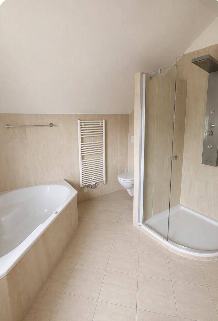 Badezimmer mit Eckbadewanne, Duschkabine, wandhängendem WC und beheiztem Handtuchhalter.