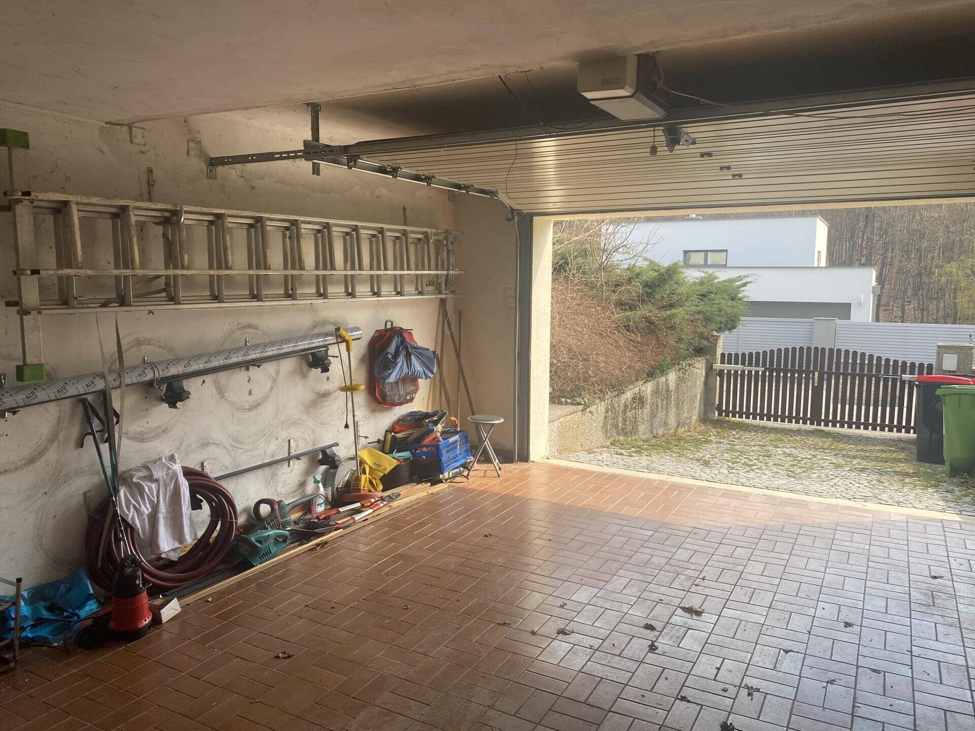 Geräumige Garage mit Fliesenboden, Stauraum und Blick auf die Einfahrt.