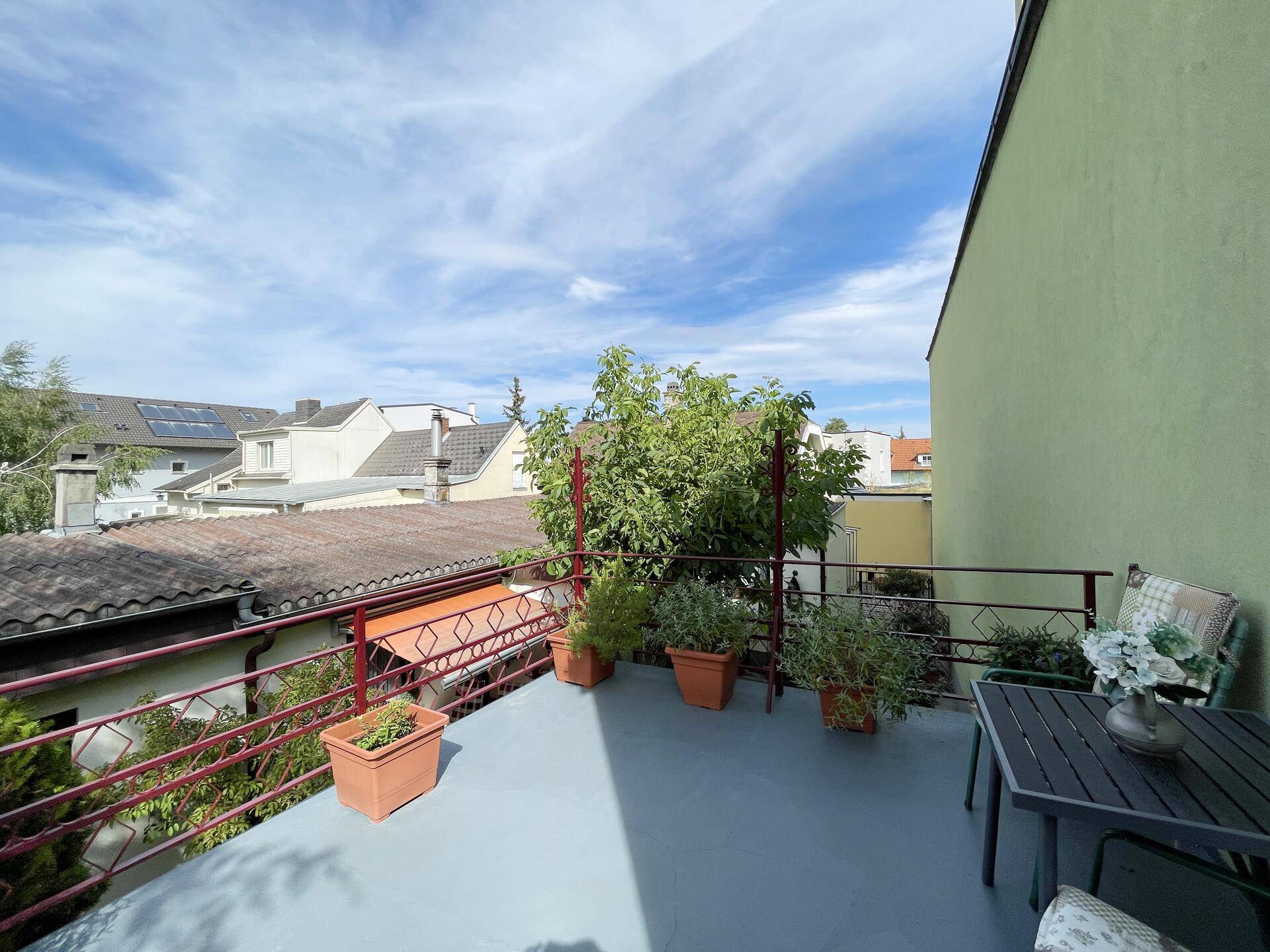 Sonniger Terrassenbereich mit Topfpflanzen, Sitzgelegenheiten und weitem Blick.