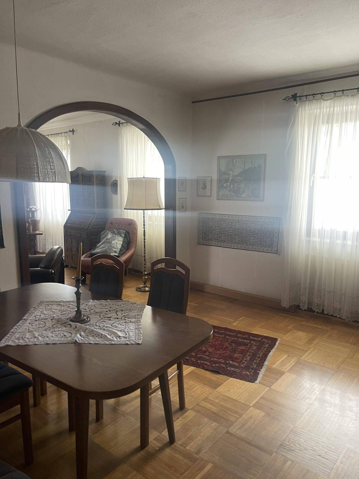 Heller Essbereich mit Holztisch und Parkettboden, offen zum angrenzenden Wohnbereich.