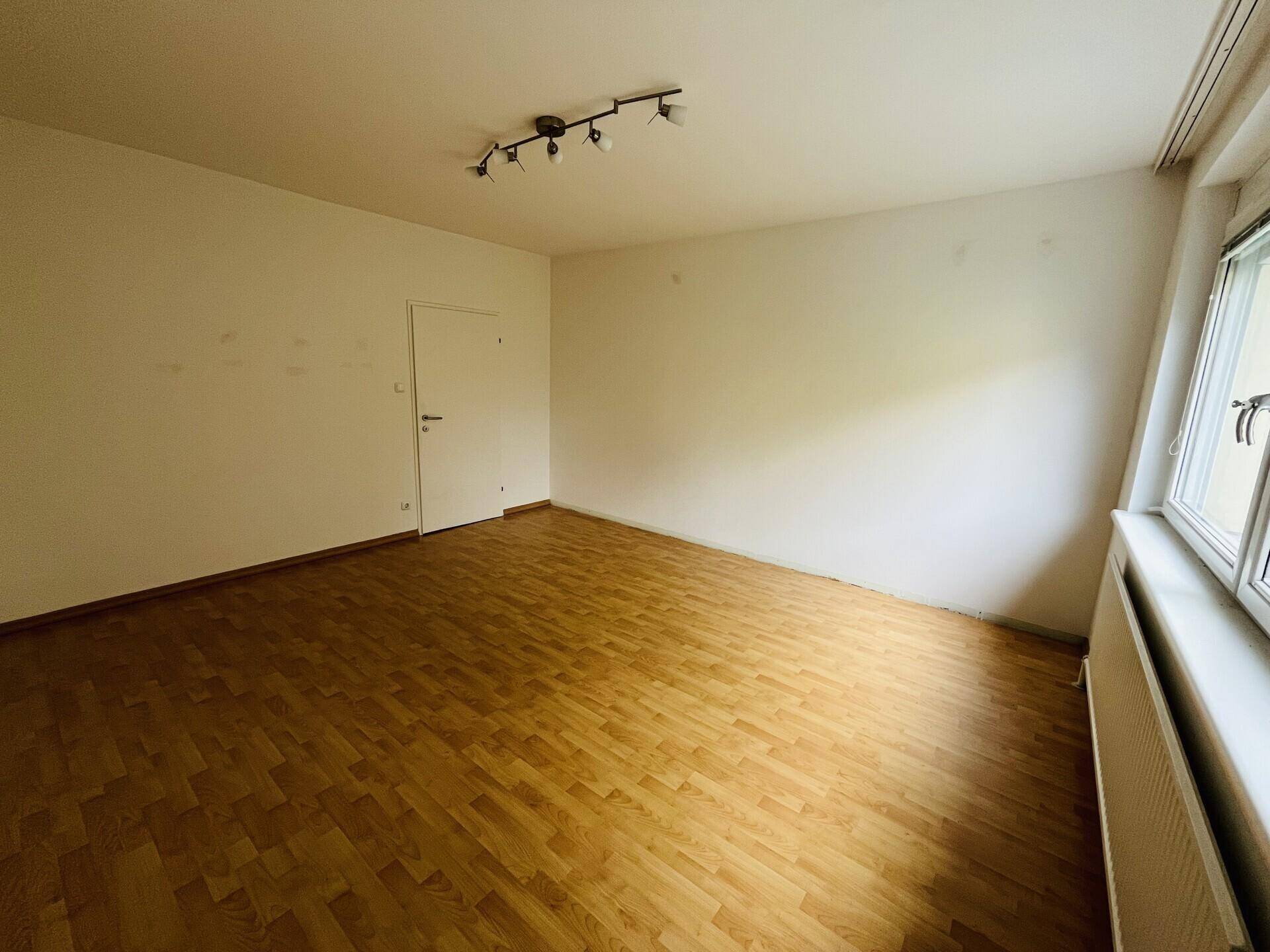 Schlafzimmer mit Parkettboden und weiß gestrichenen Wänden.