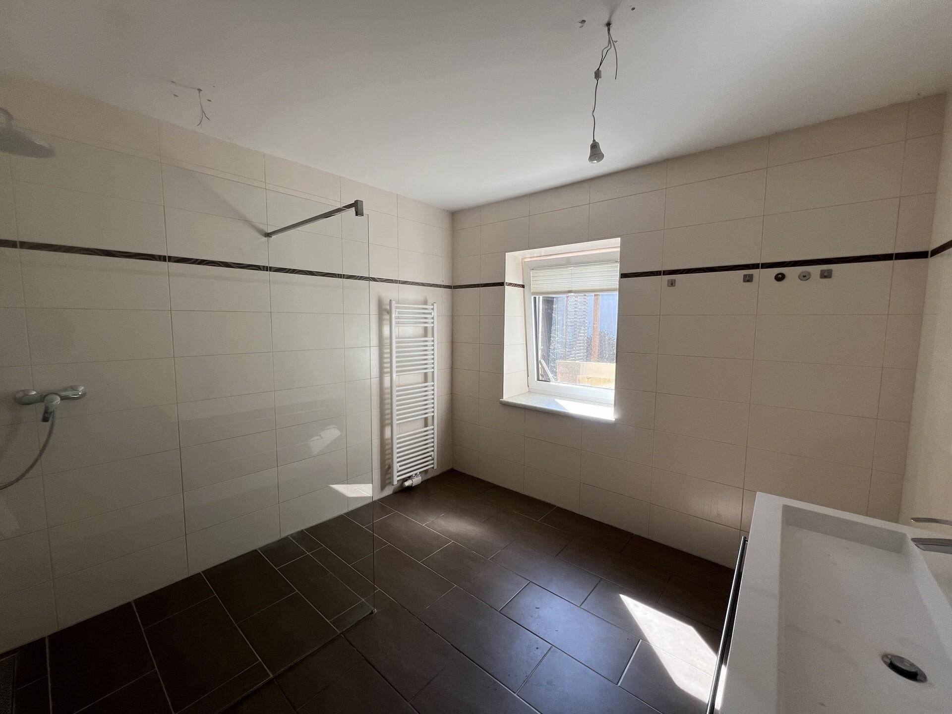 Helles Badezimmer mit Fenster, begehbarer Dusche und modernem Waschtisch.