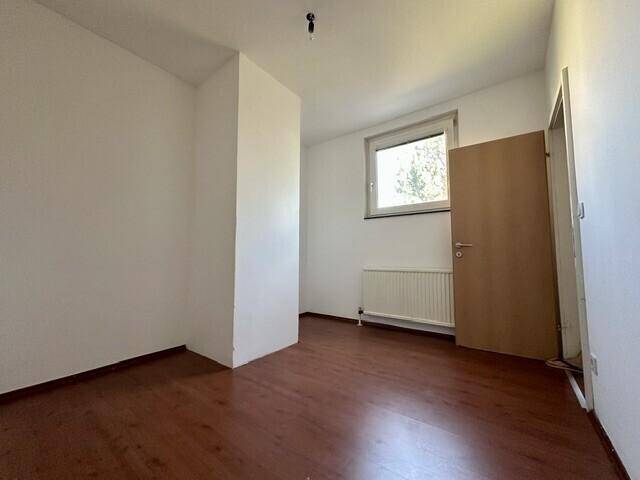 Helles Zimmer mit Laminatboden, weißen Wänden und einer Tür, bereit zur individuellen Gestaltung.