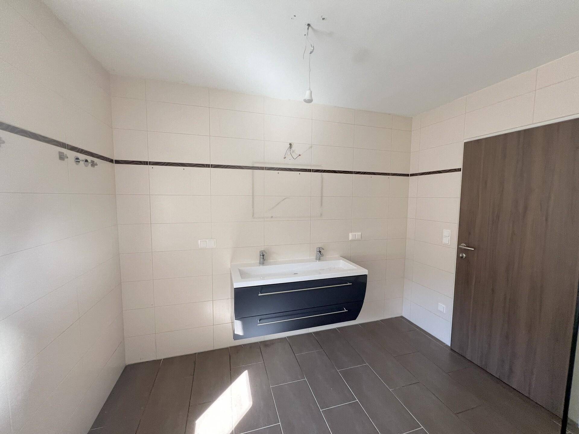 Modernes Badezimmer im Bau mit Doppelwaschbecken und hellen Fliesen.