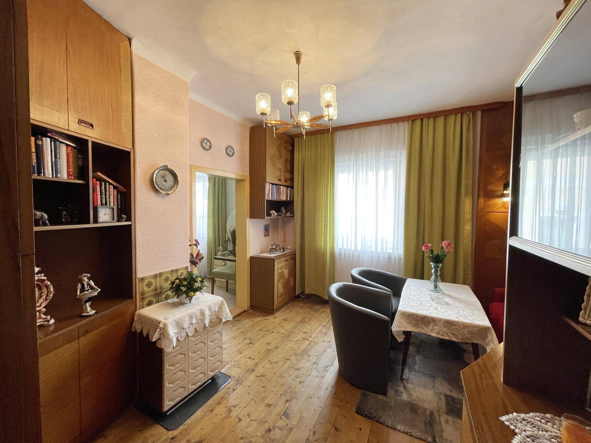 Geräumiges Wohnzimmer mit Holzdielenboden, Holzmöbeln und einem Kronleuchter.