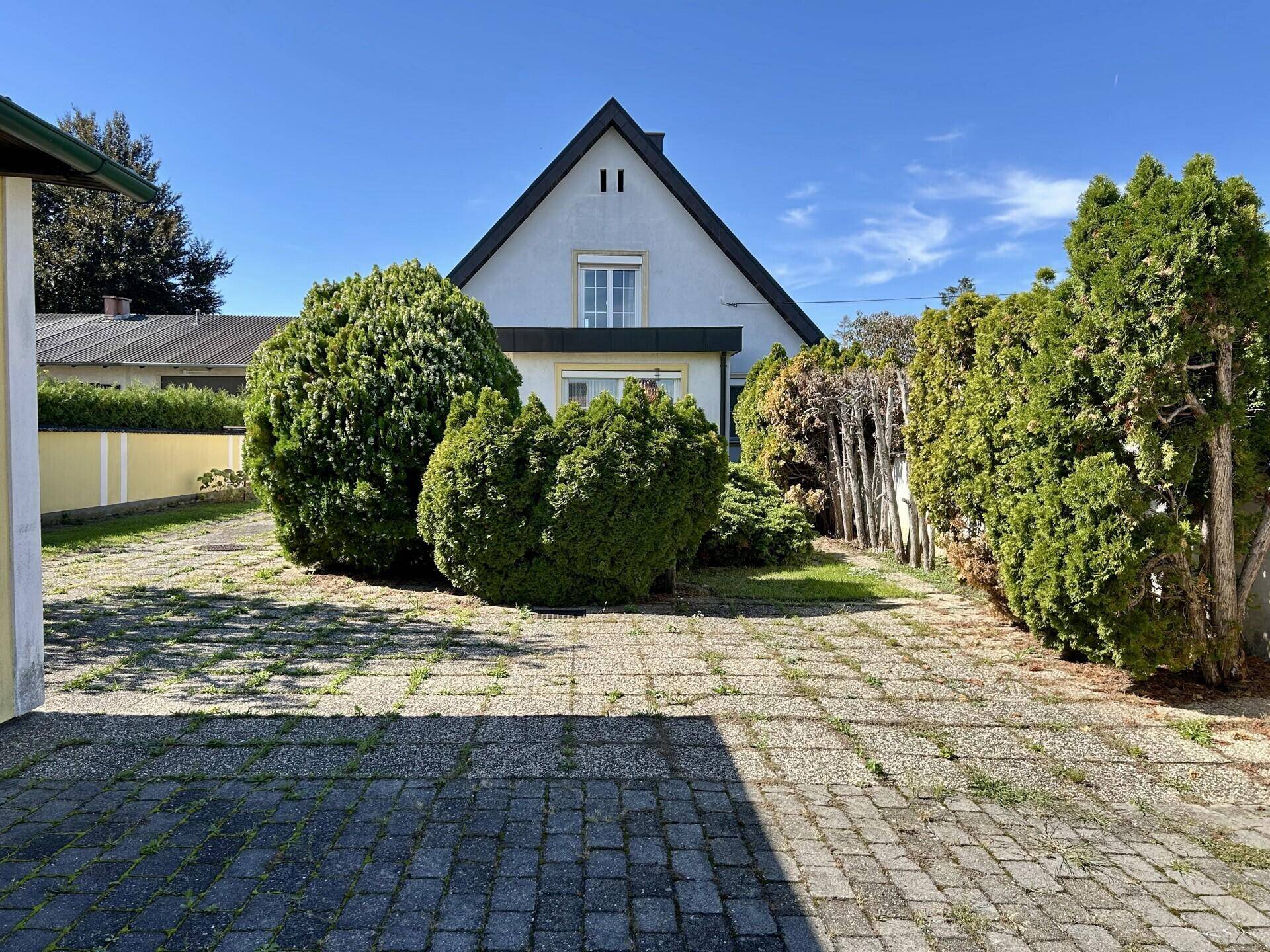 Vorderansicht des Hauses mit gepflegtem Vorgarten und breiter Einfahrt.