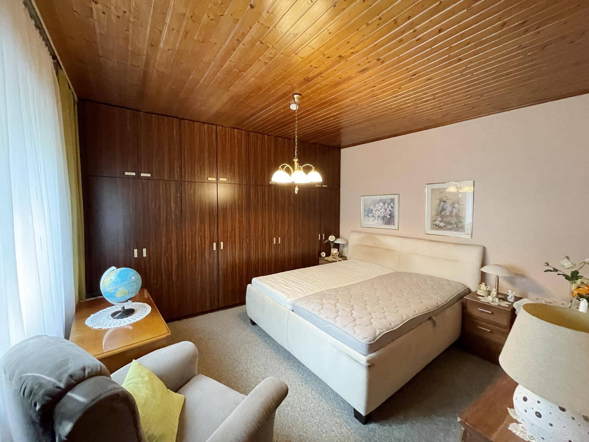 Schlafzimmer mit Doppelbett, großen Holzschränken und Teppichboden.