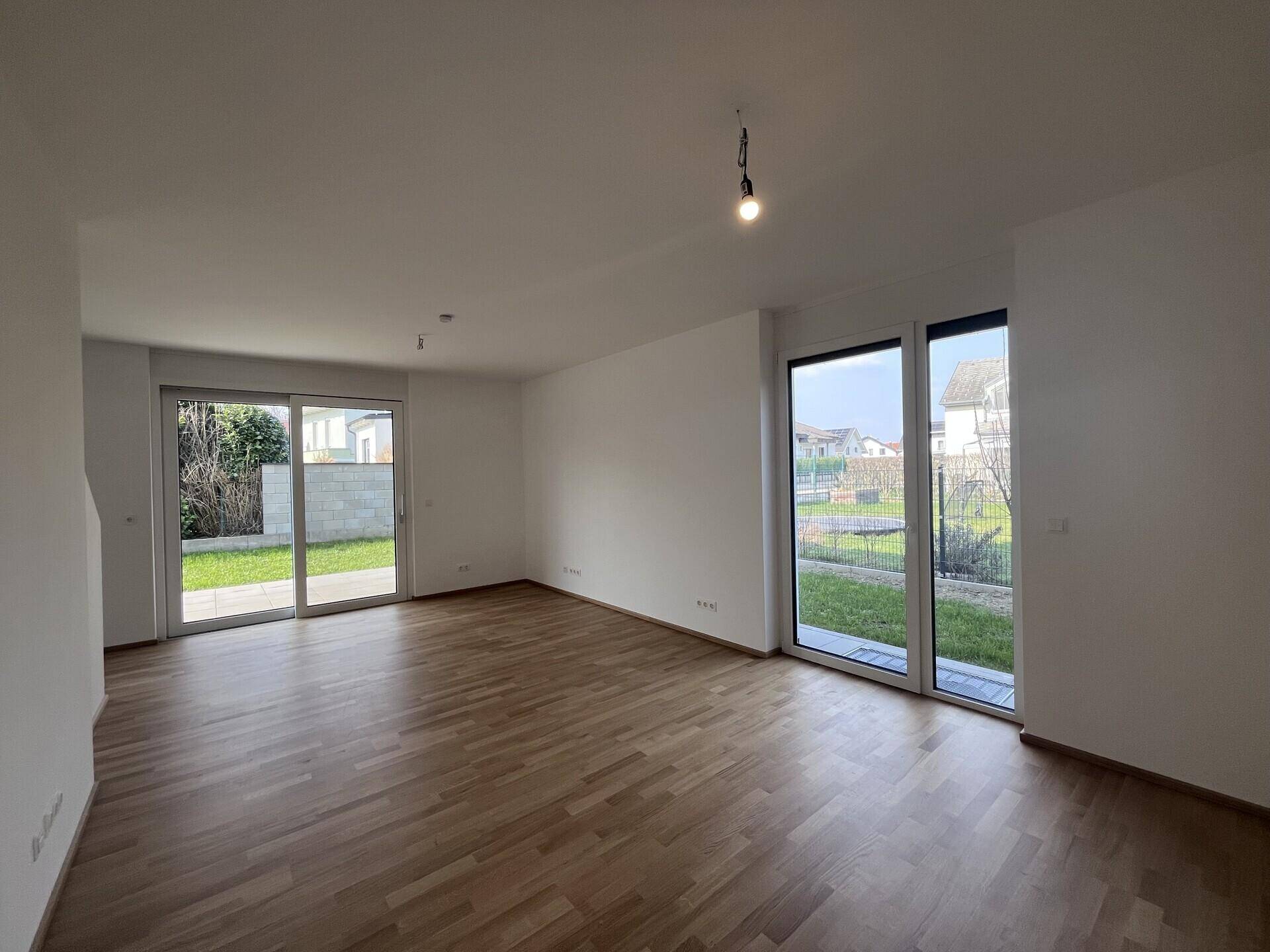 Helles Wohnzimmer mit Parkettboden und großen Schiebetüren zum Garten.