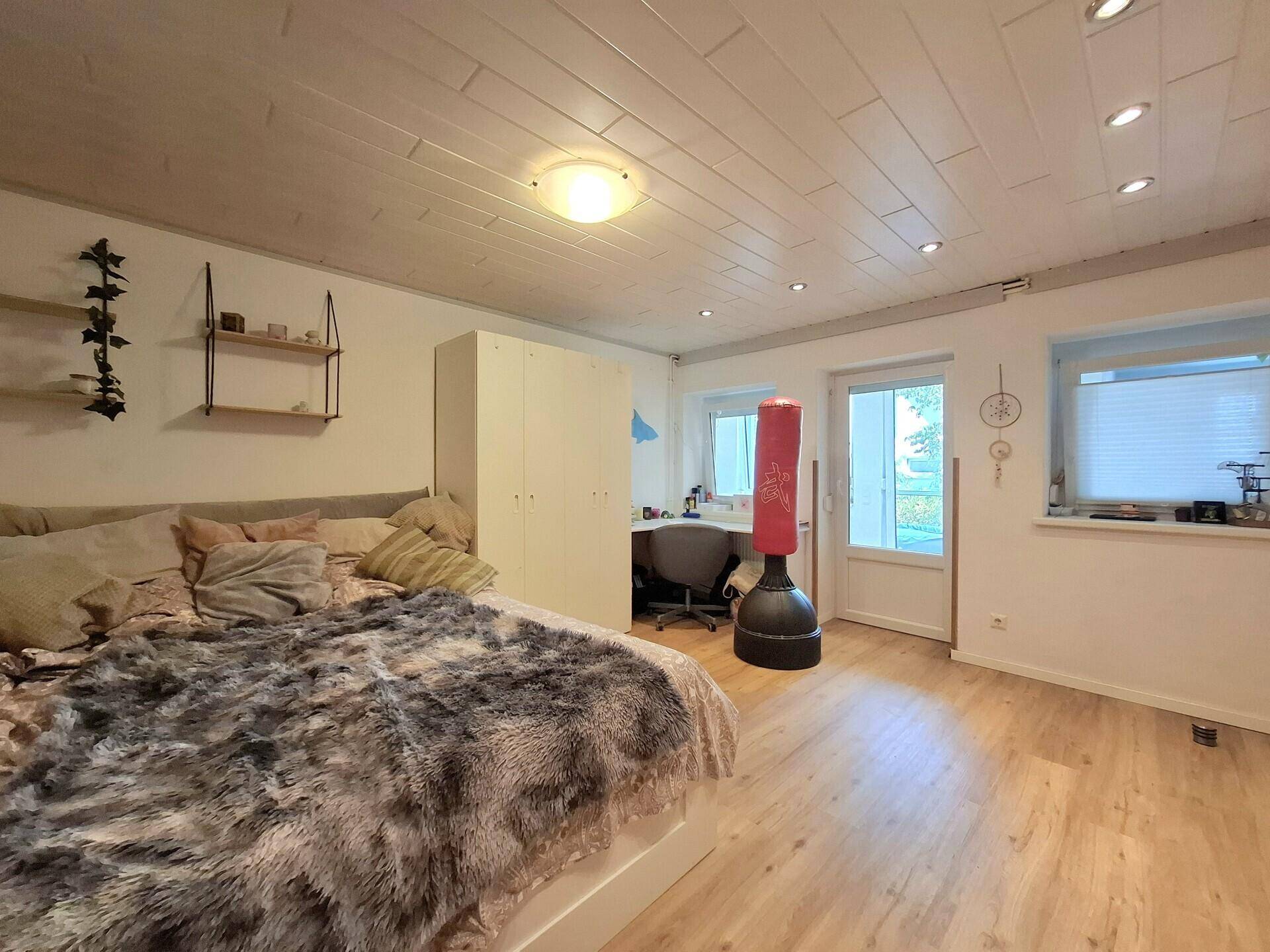 Schlafzimmer mit Zugang zum Außenbereich, Holzbalkendecke und viel natürlichem Licht.