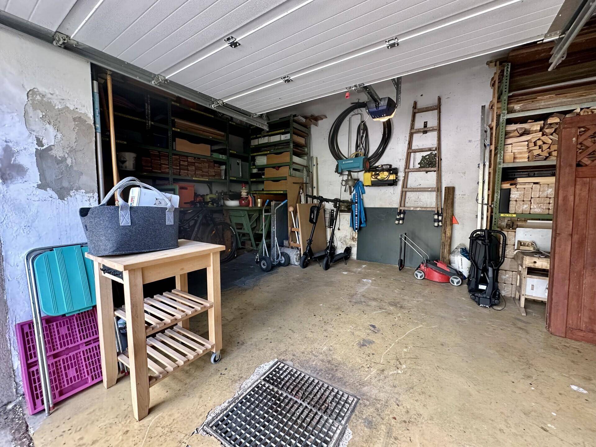 Garage mit Rolltor, Lagerregalen und Platz für Fahrzeuge und Geräte.